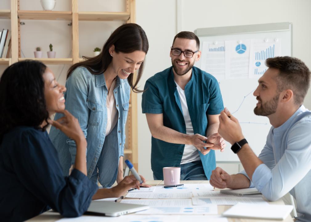 Coworkers smile and talk together in a meeting room