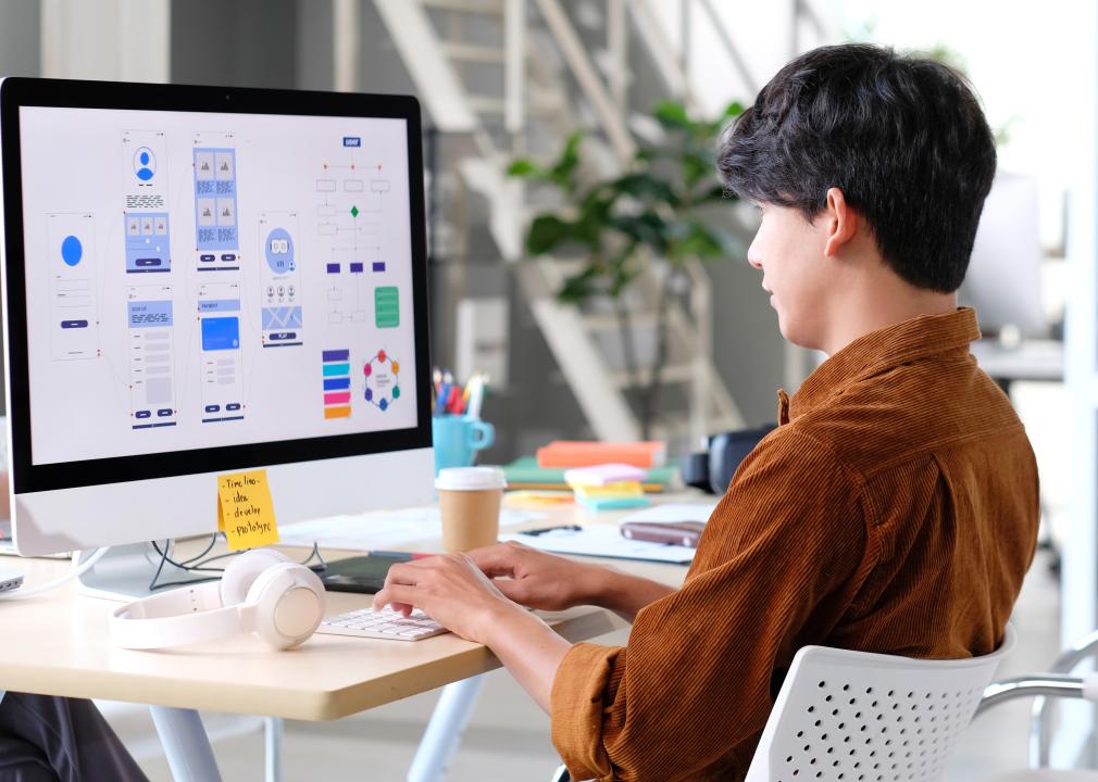 UX designer working on smartphone application at a desk in an office.