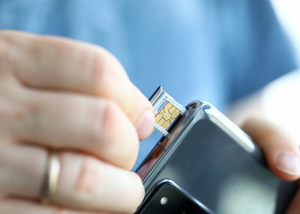 Hands pulling a SIM card out of a smartphone.