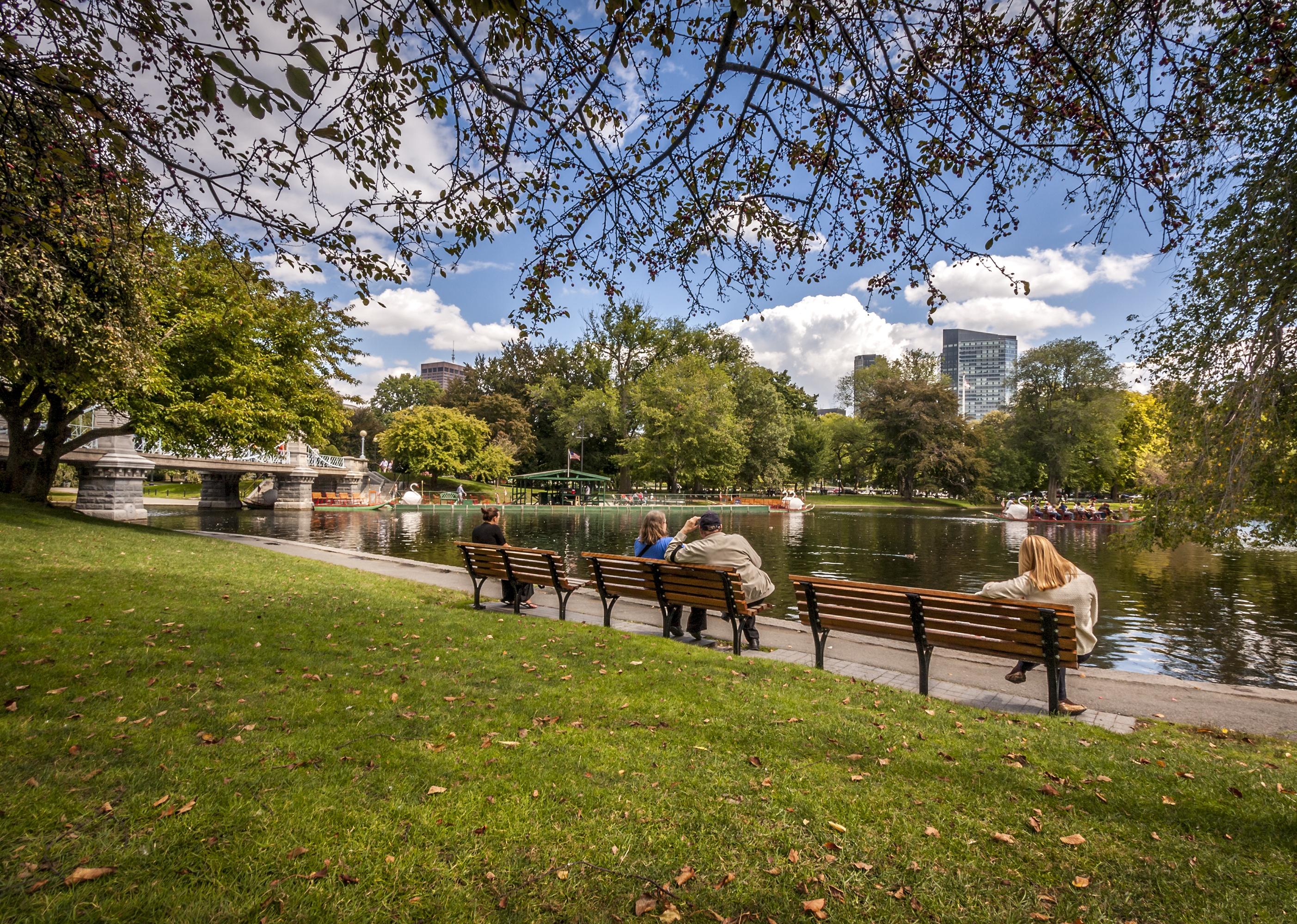 People on benches visiting the Boston Public Garden.