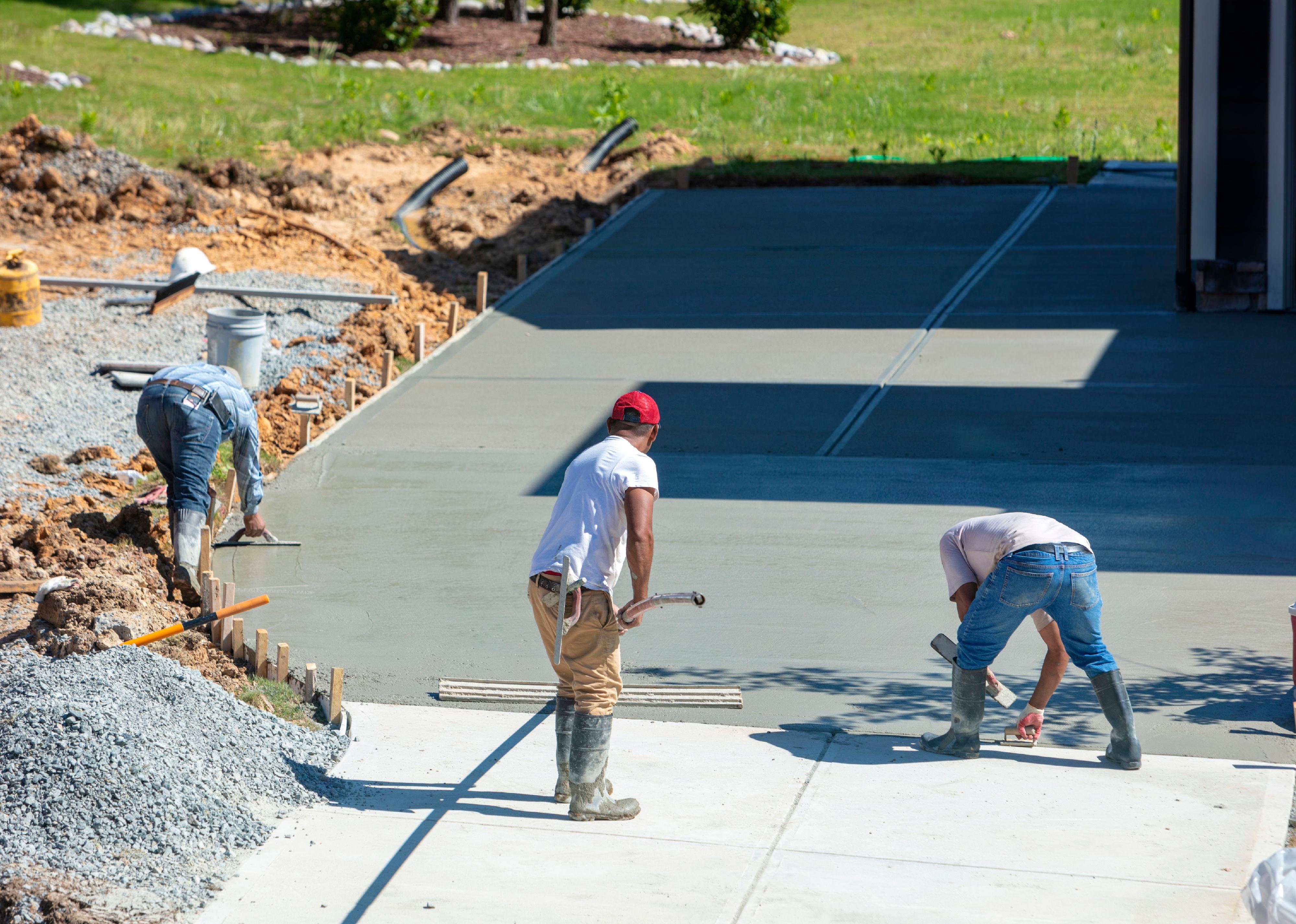 People working on a new concrete driveway at a residential home.