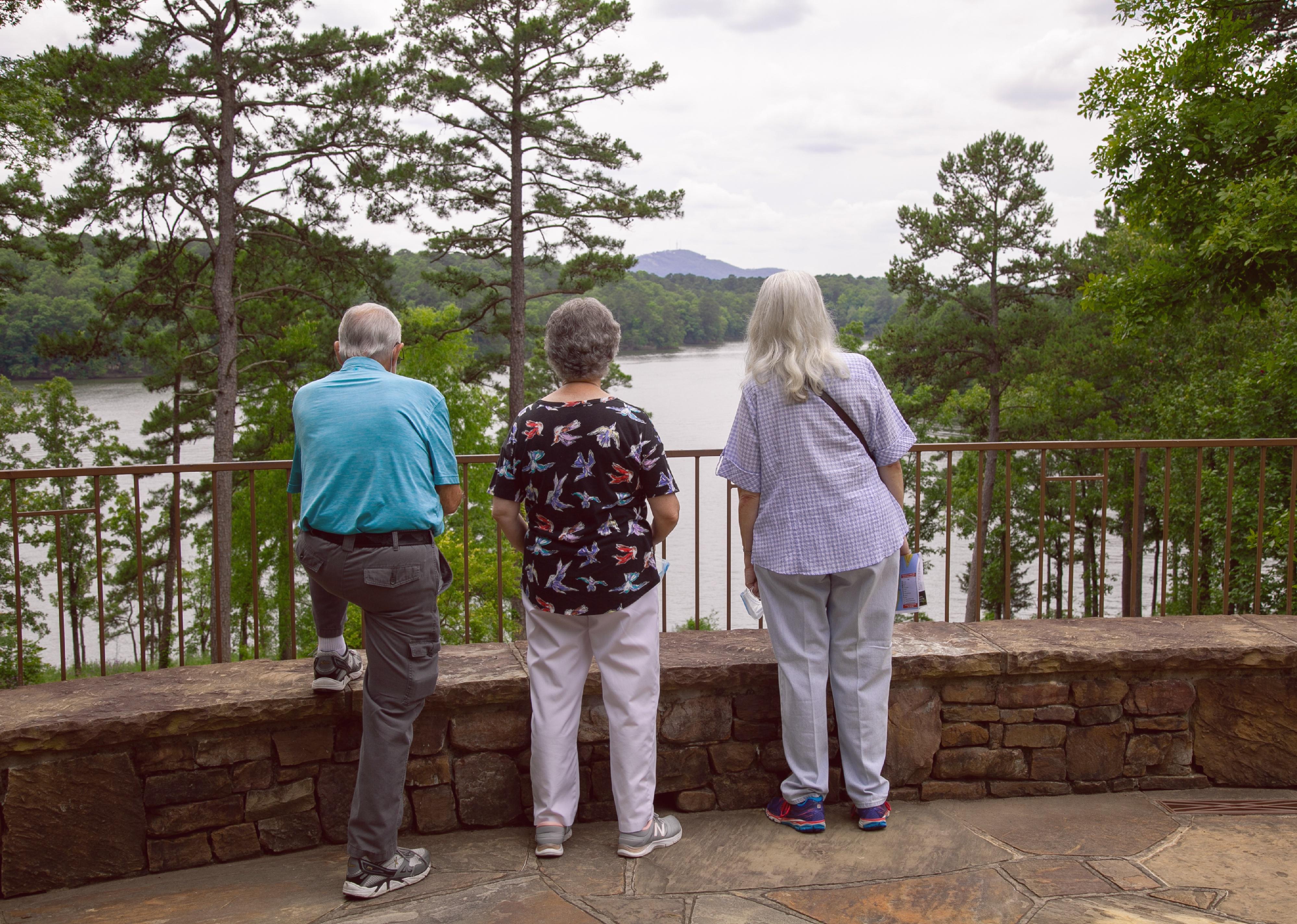 Elderly people enjoy a view of a lake.