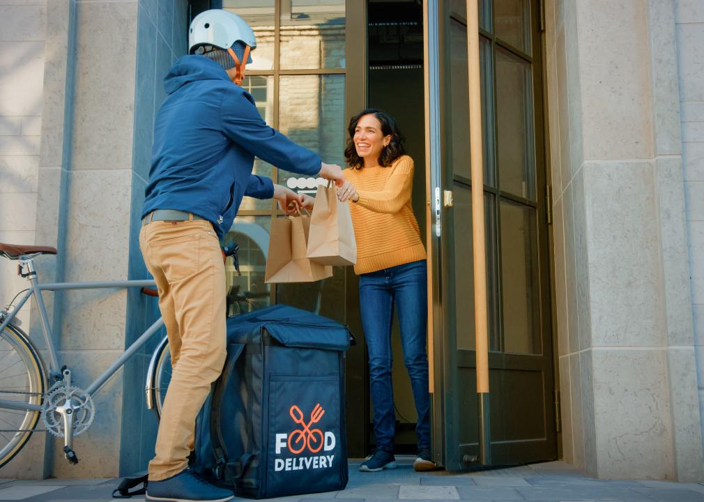 Courier delivers food to woman in urban building