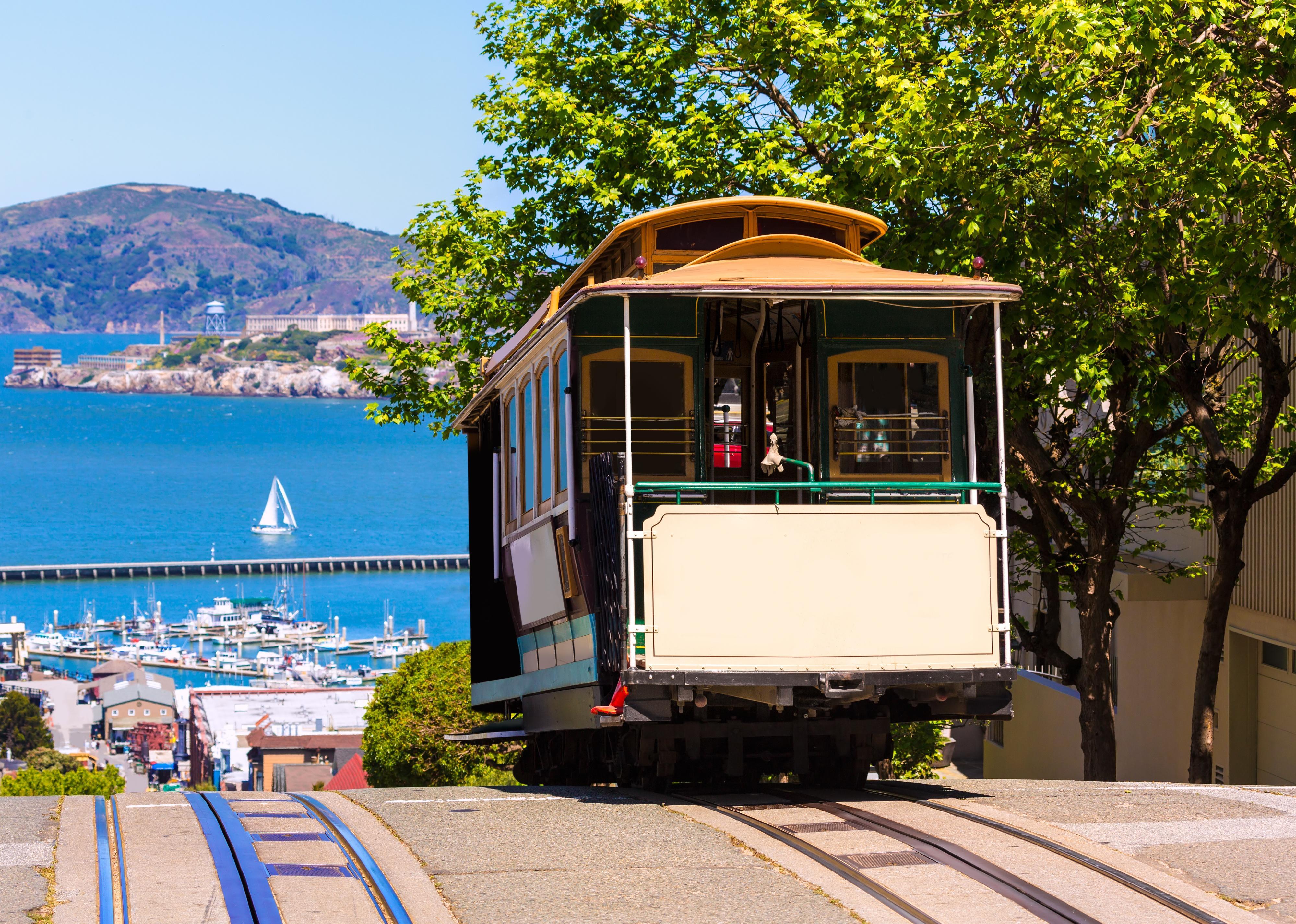 An iconic cable car reaches the top of a hill in San Francisco.