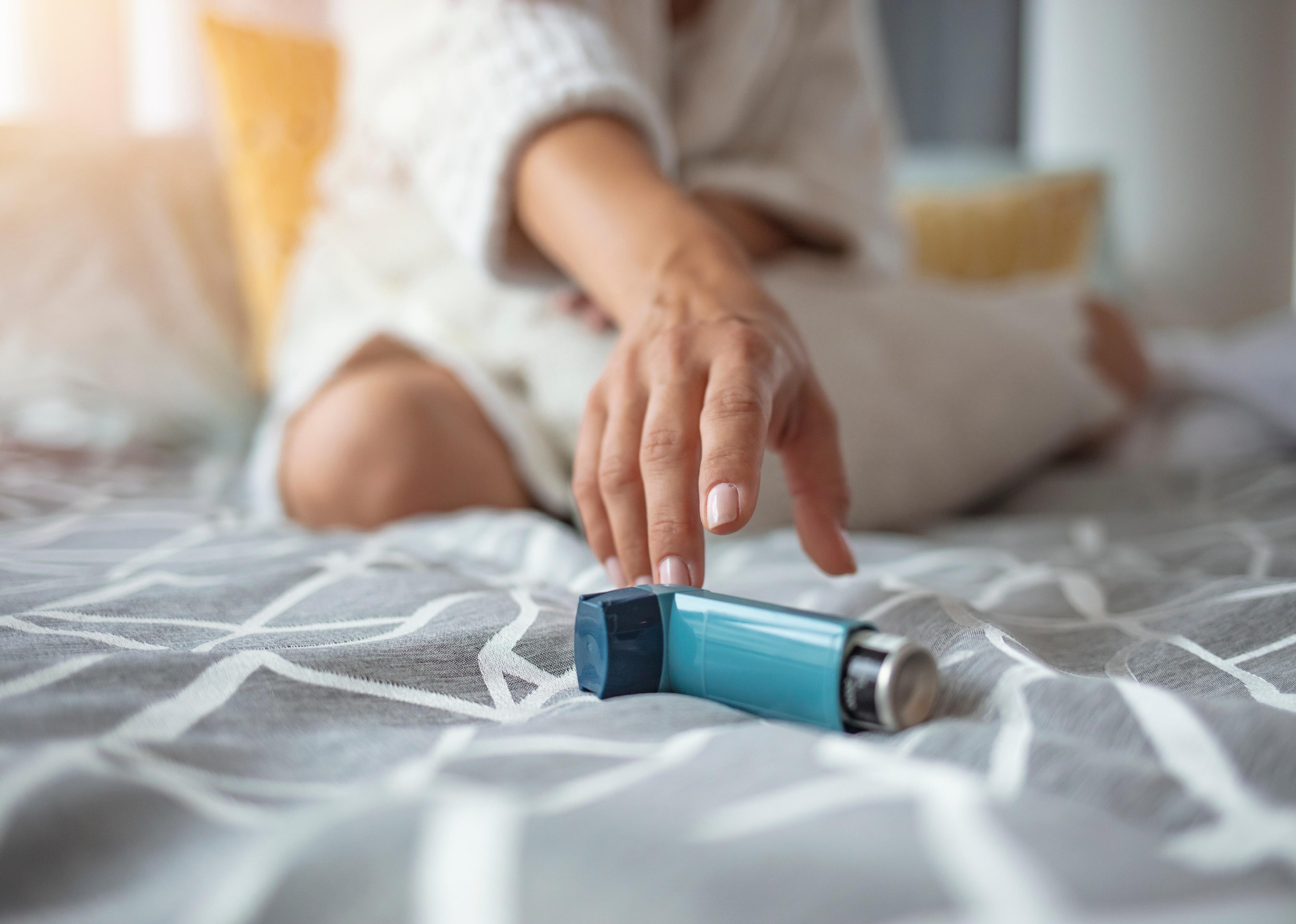 Person reaching for an asthma inhaler.