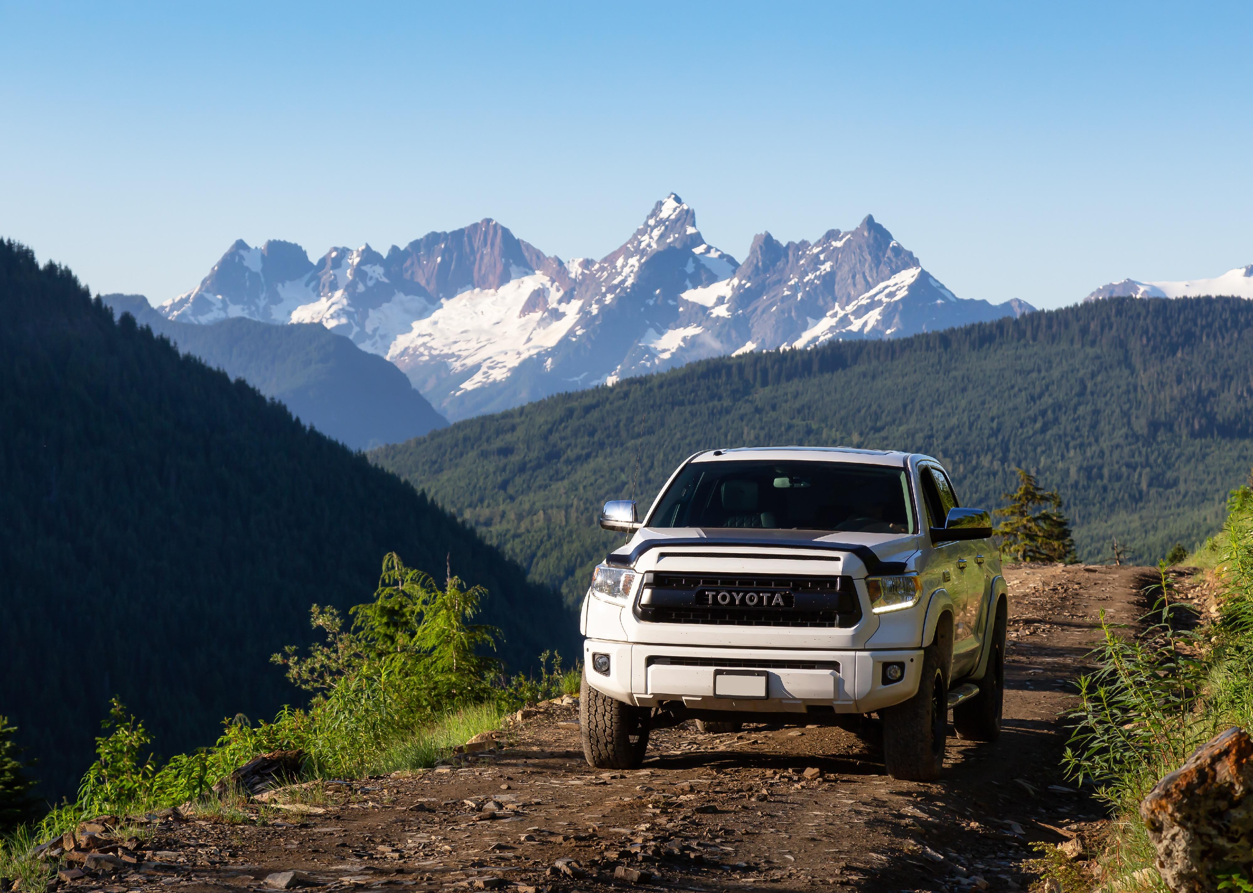 Toyota Tacoma riding on trails in the mountains during a sunny morning.