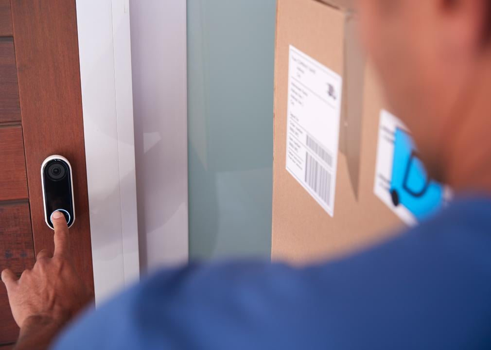 Male delivery driver ringing video door bell