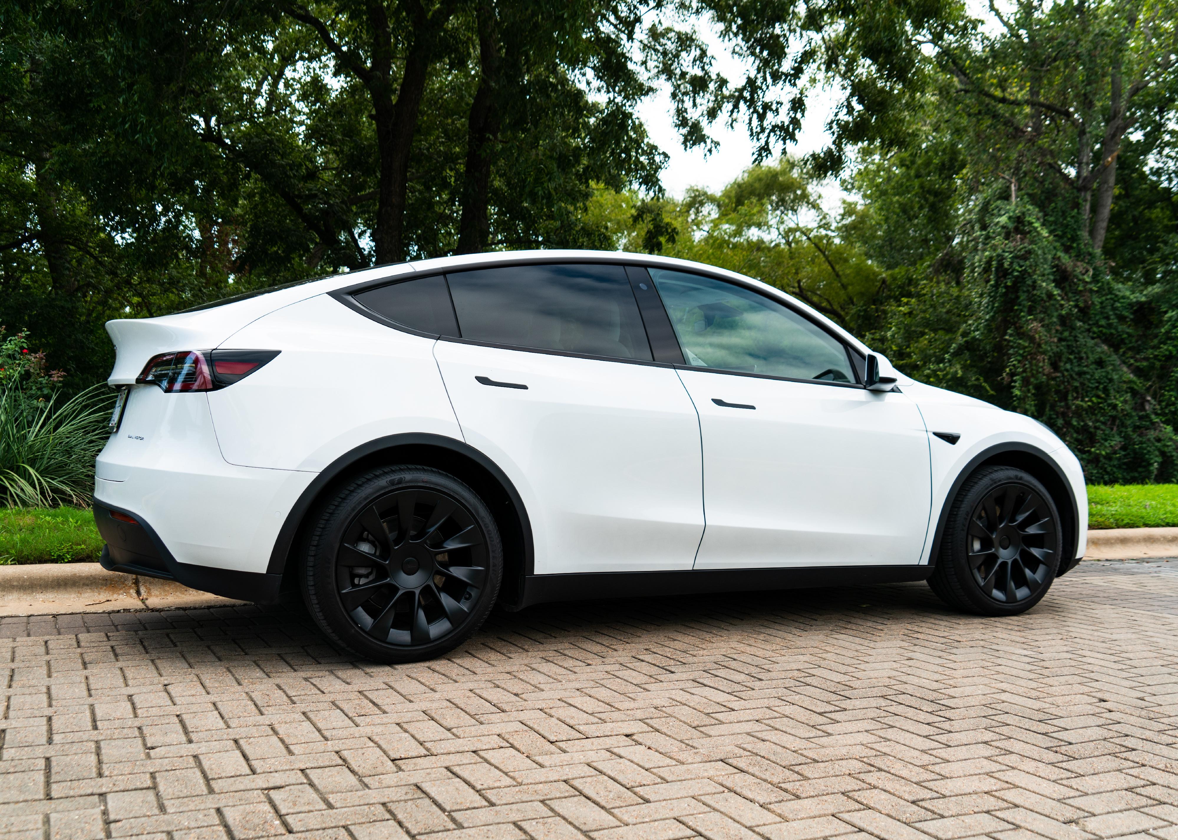 Tesla model Y with white paint and blue wheels.