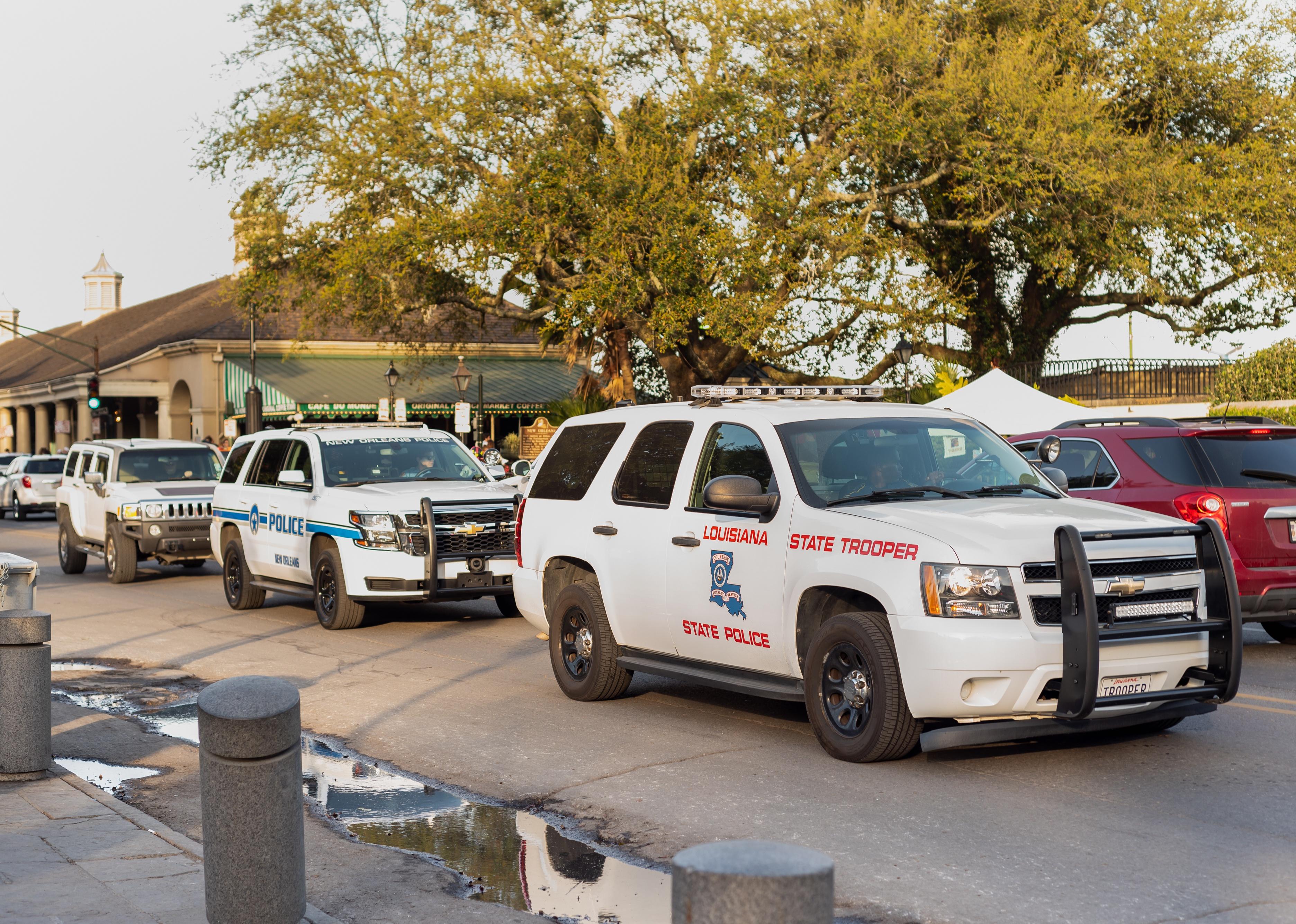 Two Louisiana police vehicles drive down Decatur street.