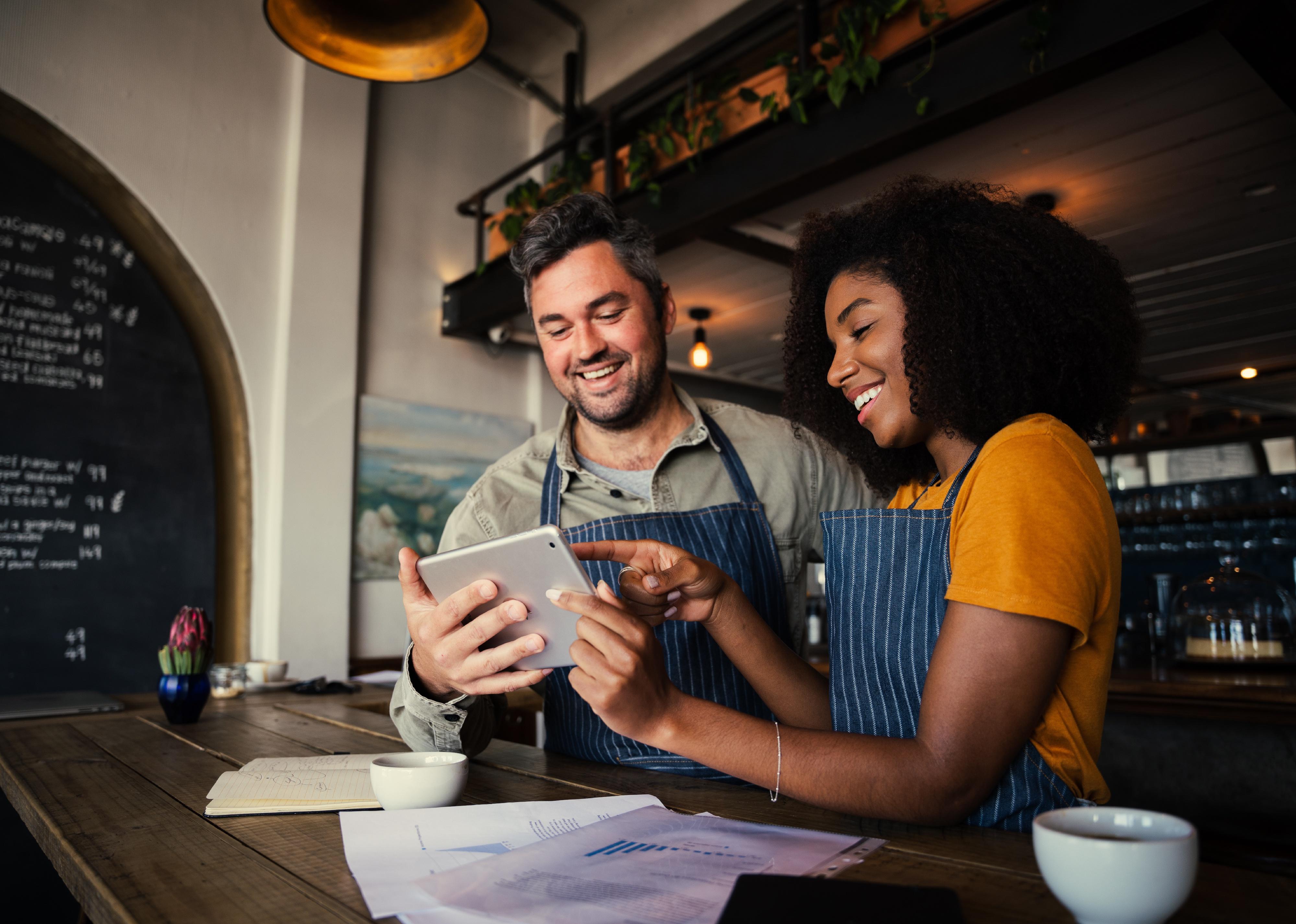 Manager and waitress laughing atdigital tablet