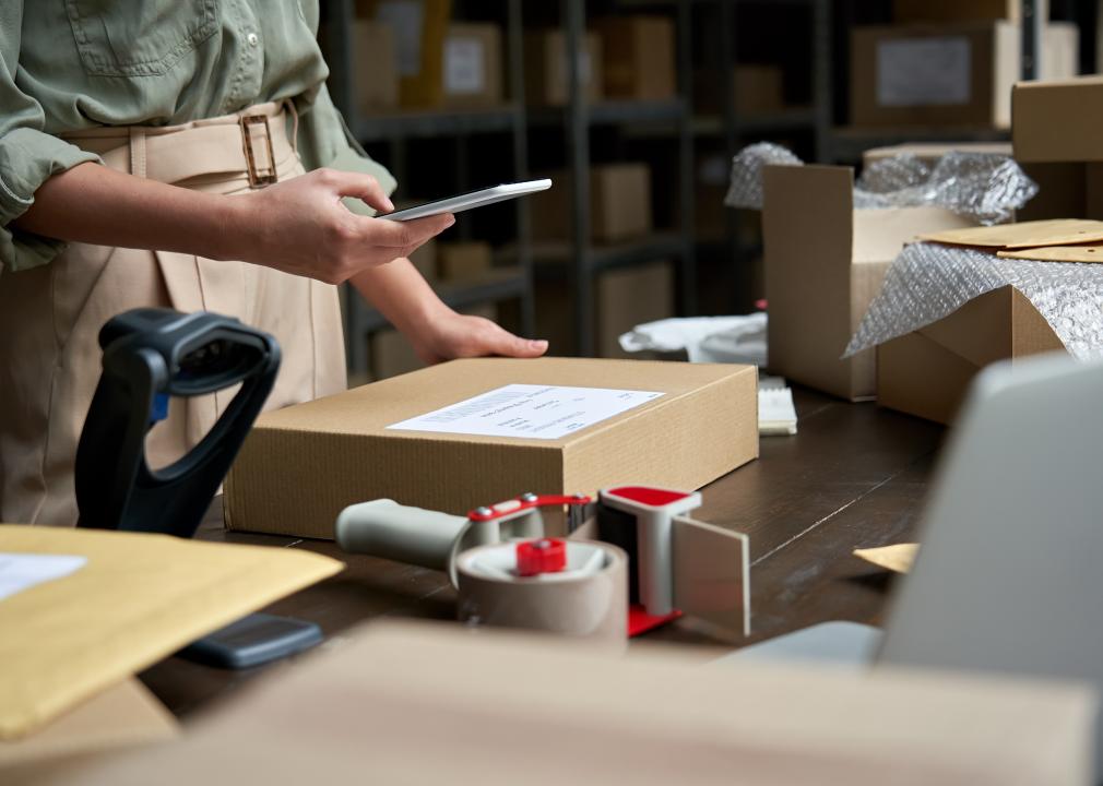 Business owner using mobile app on smartphone checking a parcel box. 