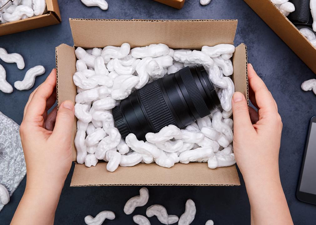 Female hands unpacking parcel with camera lens inside
