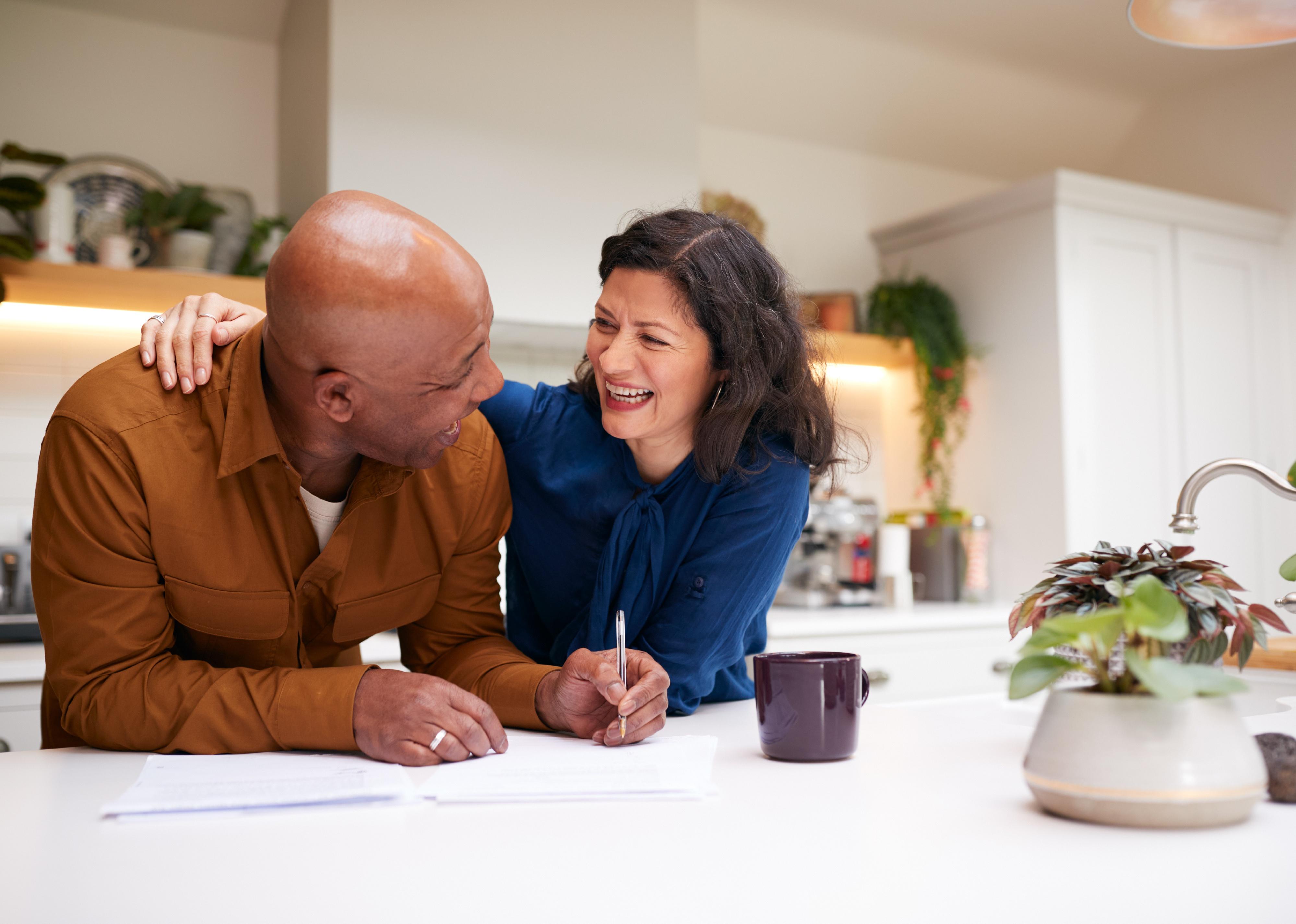 Couple reviewing and signing paperwork in kitchen.