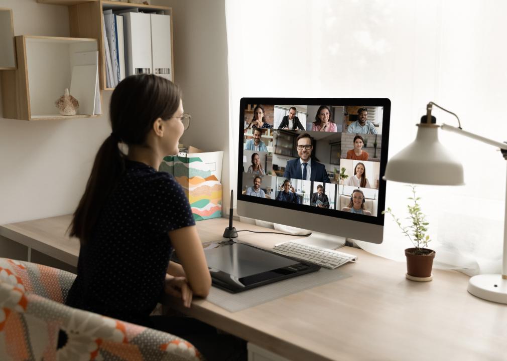 Rear view of female employee looking online video meeting