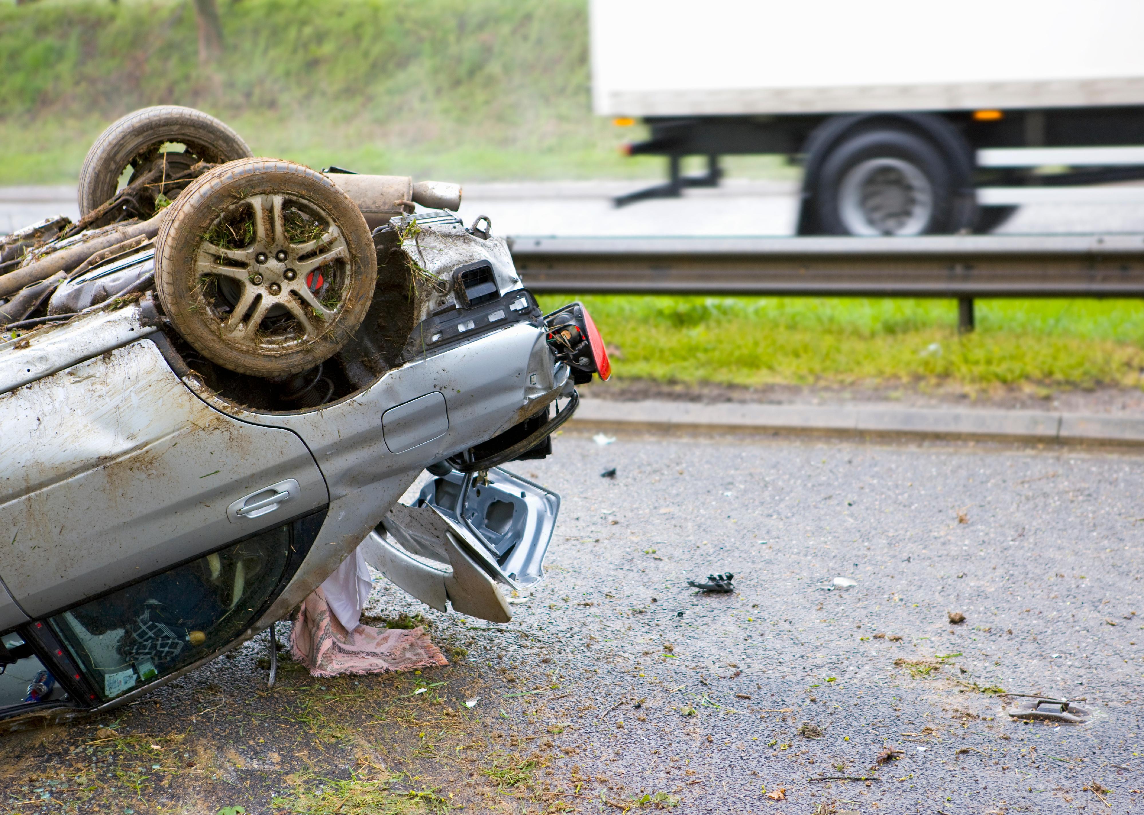 Close-up shot of the trunk of a car lying upside down after a crash on a motorway.