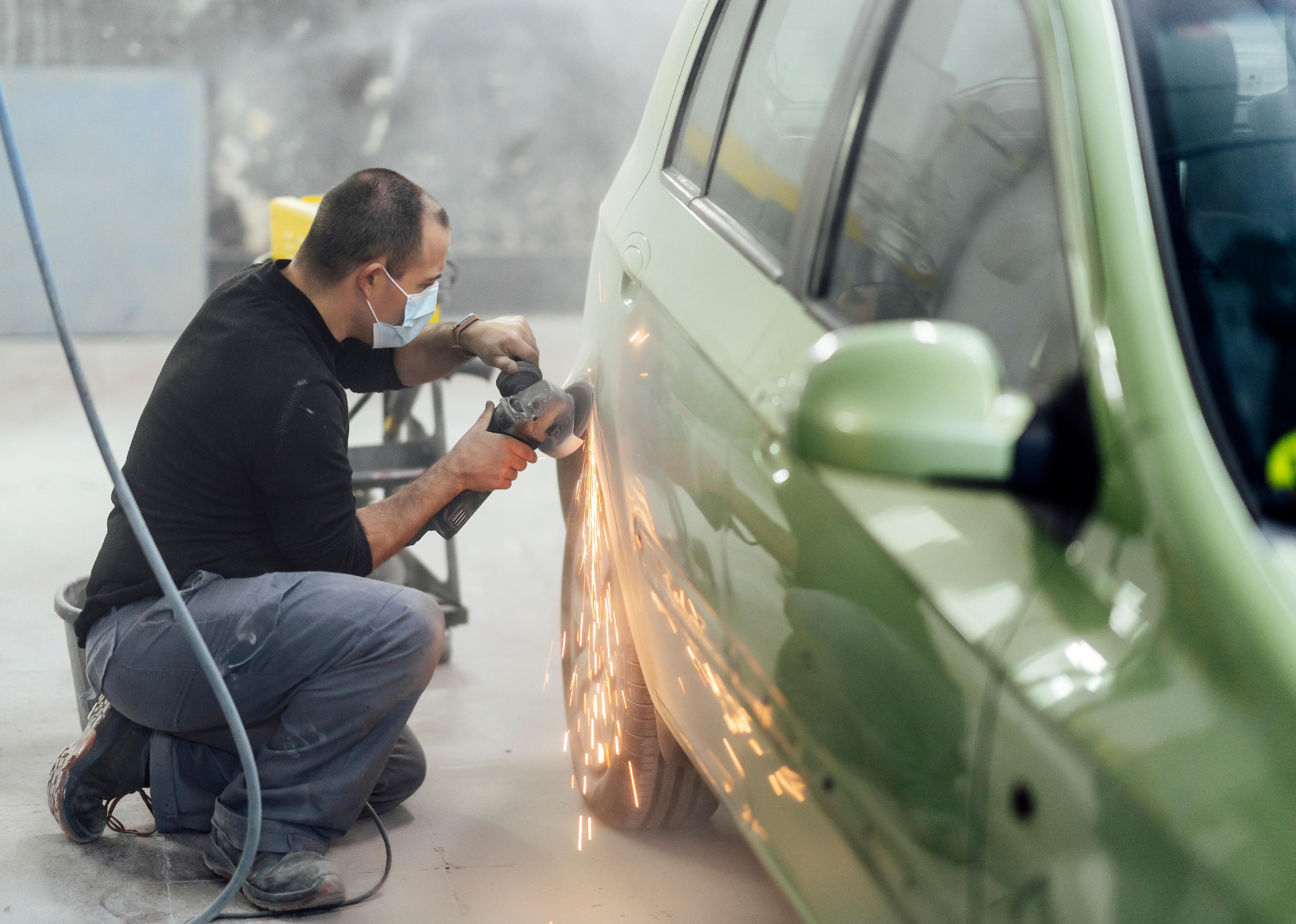 Sheet metal mechanic sanding a car with radial