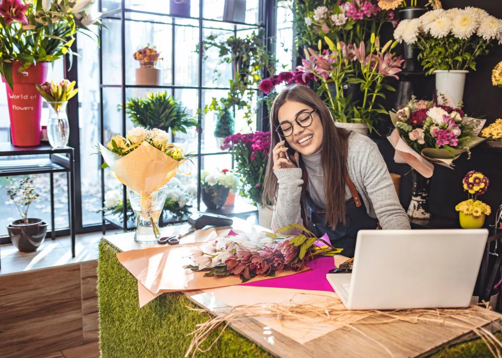 Smiling flower shop owner working on laptop computer