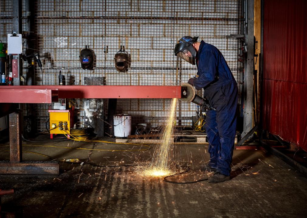 Male worker cutting metal in a workshop with sparks flying