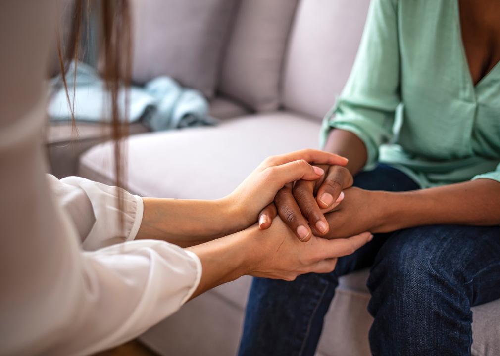 Close up of a Psychologist holding hands of a female patient.
