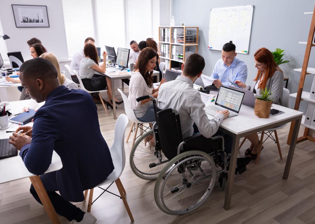 Group of people working at table including man in wheelchair