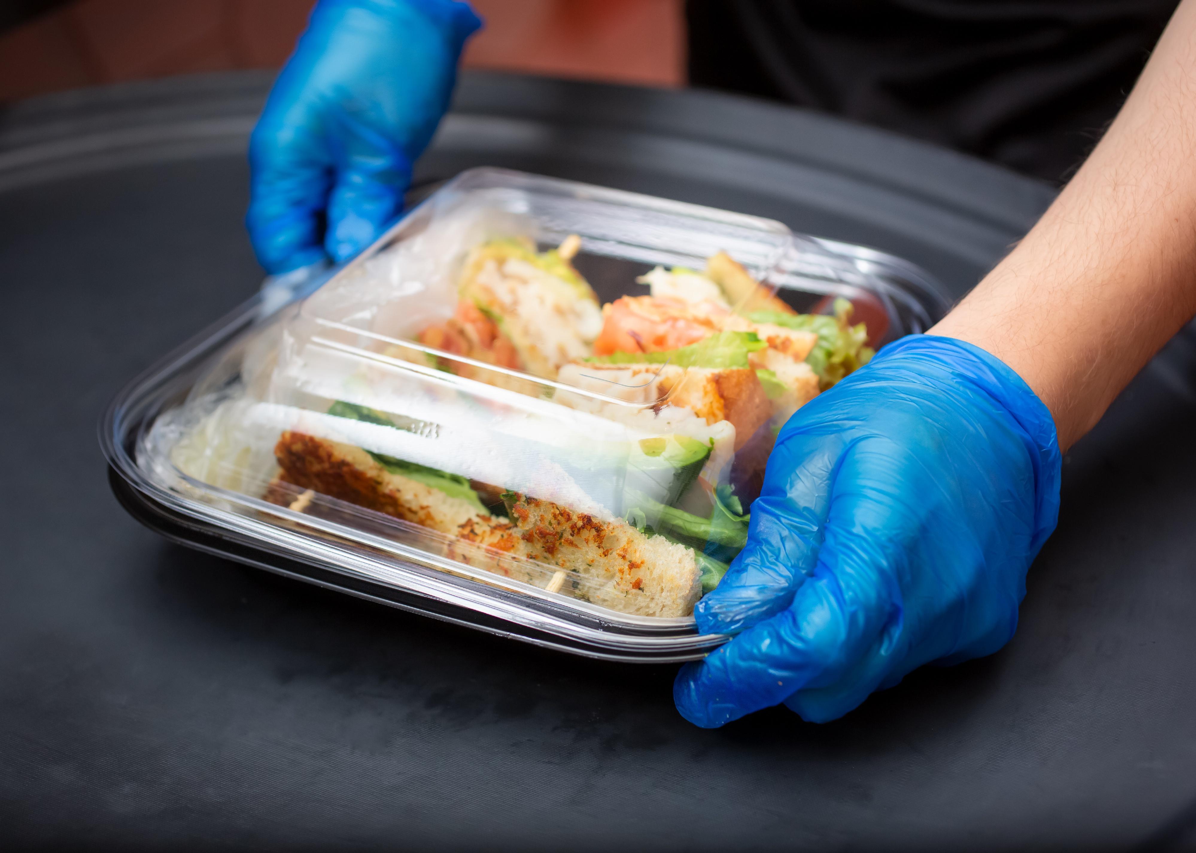 Close up of an employee preparing a to-go food container.