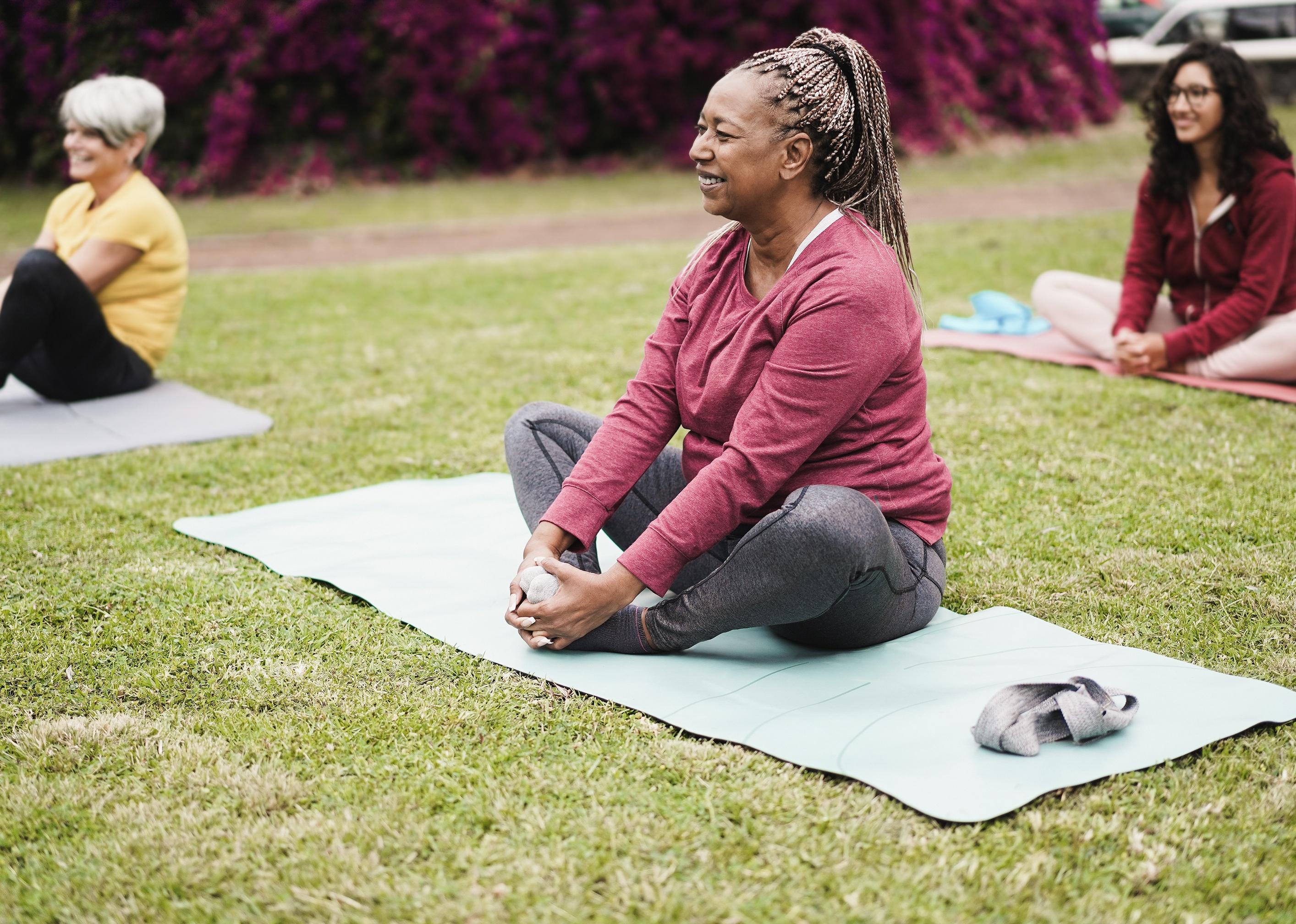 Smiley people doing yoga class at city park.