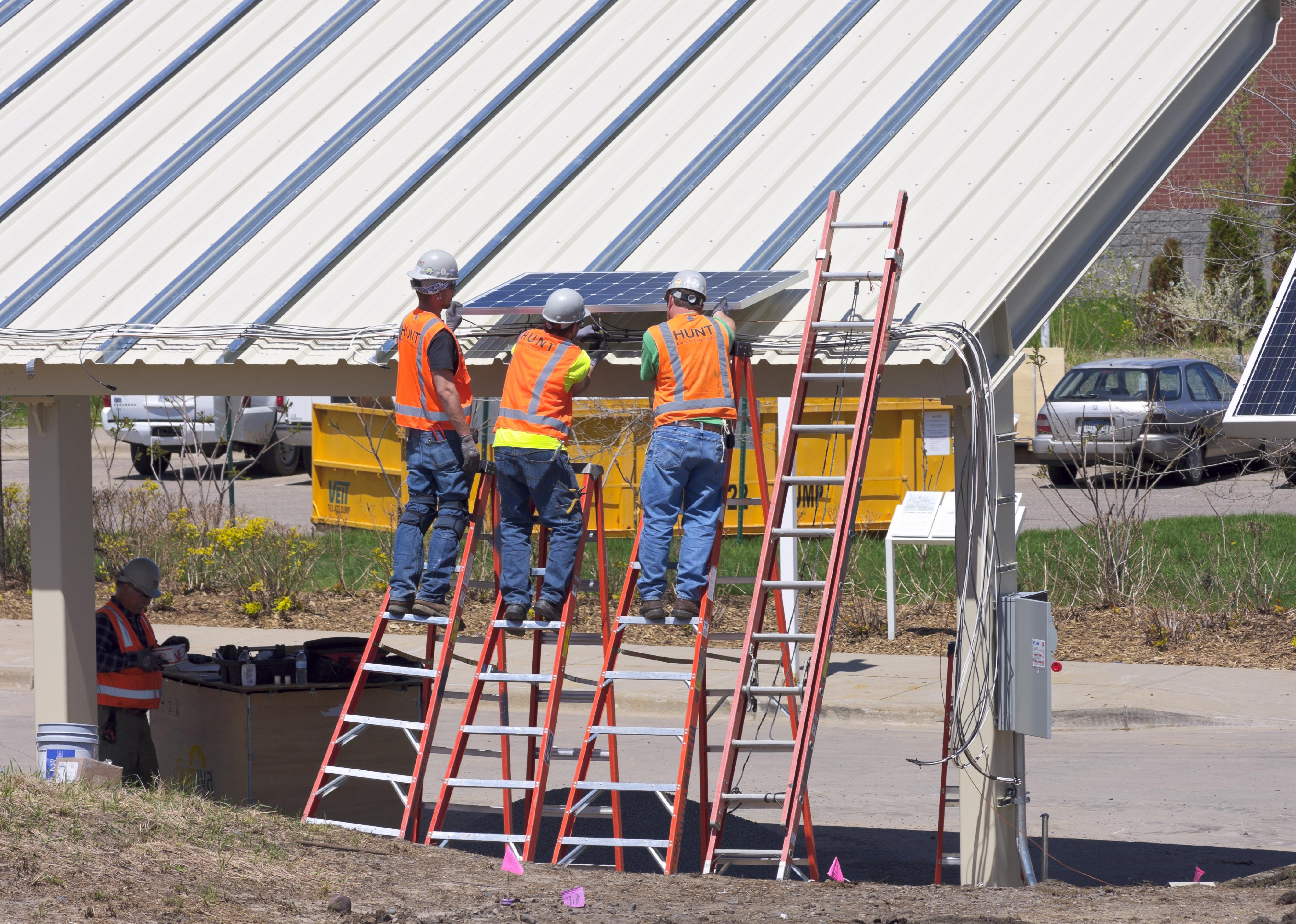 Workers install solar carport