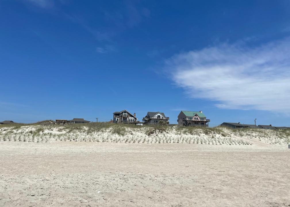 Coastline and beachfront houses behind dunes.