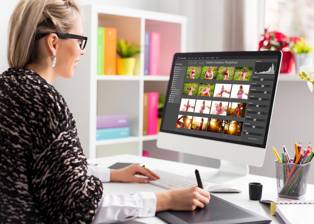 Woman working with digital photo library on desktop computer and editing photos.