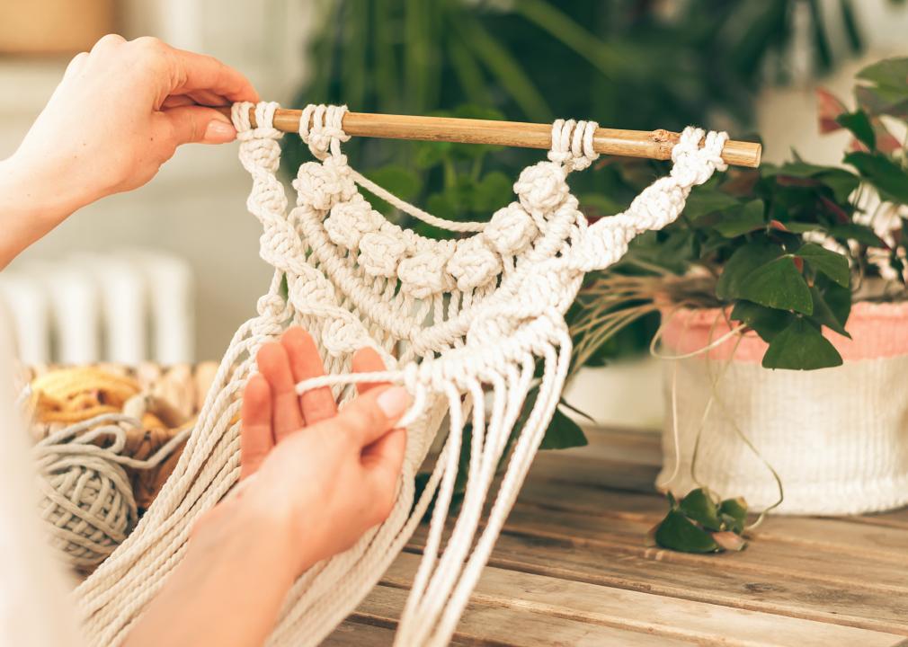 Close up of women's hands weaving macrame.