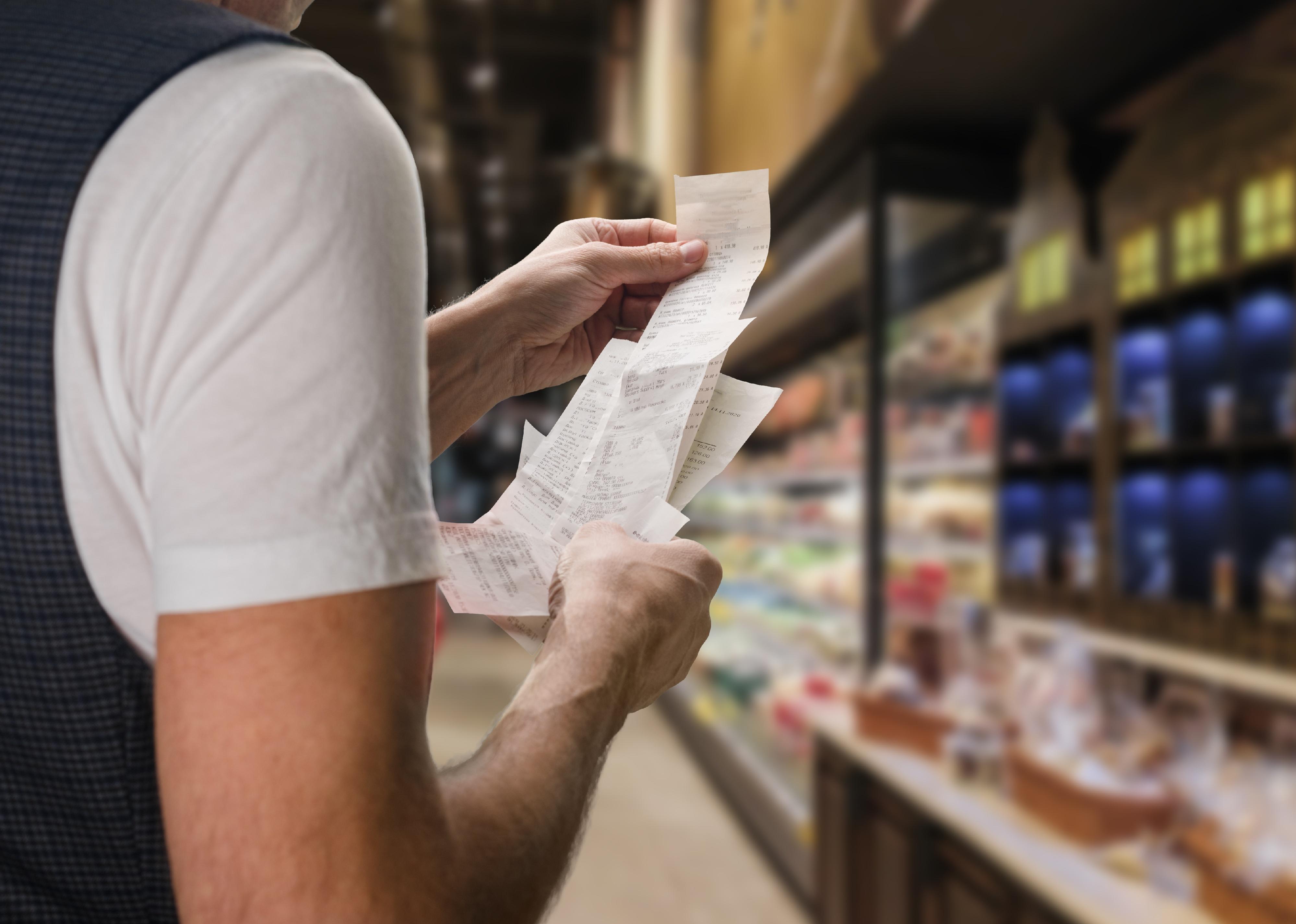 Closeup of young man holding receipt in supermarket