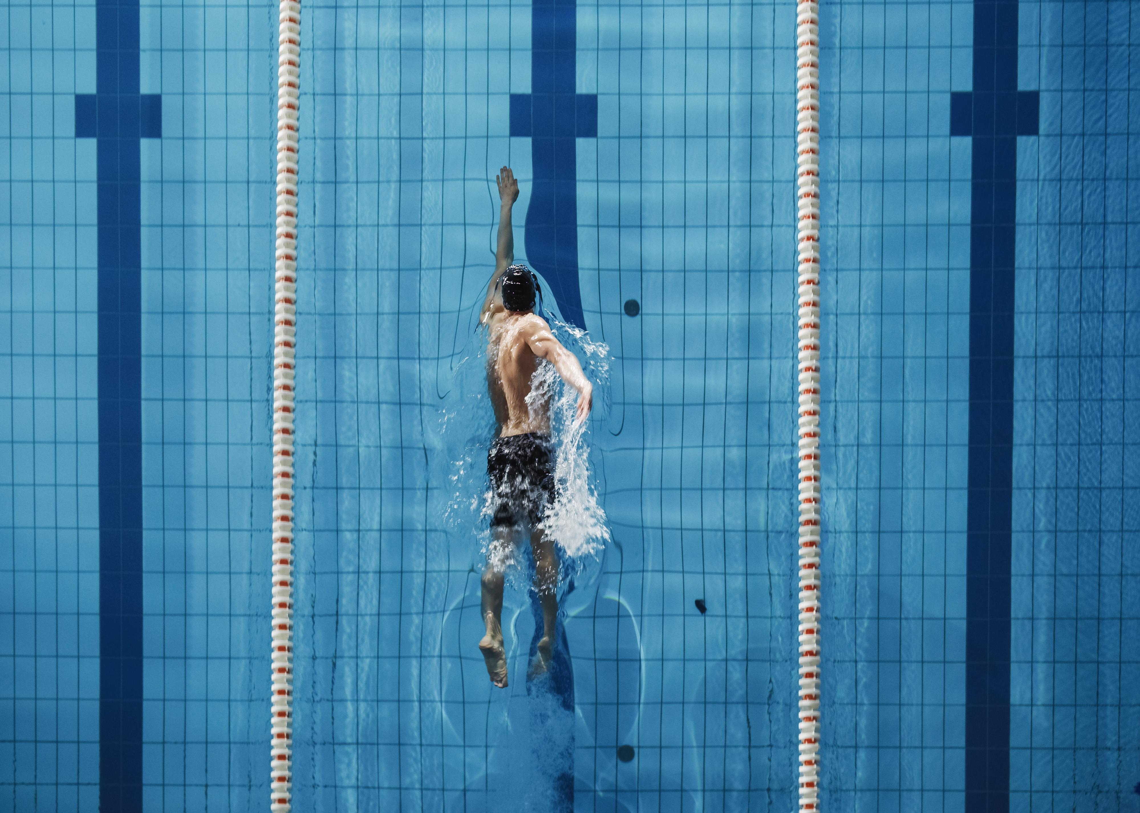 Aerial top view of a male swimming in a pool.