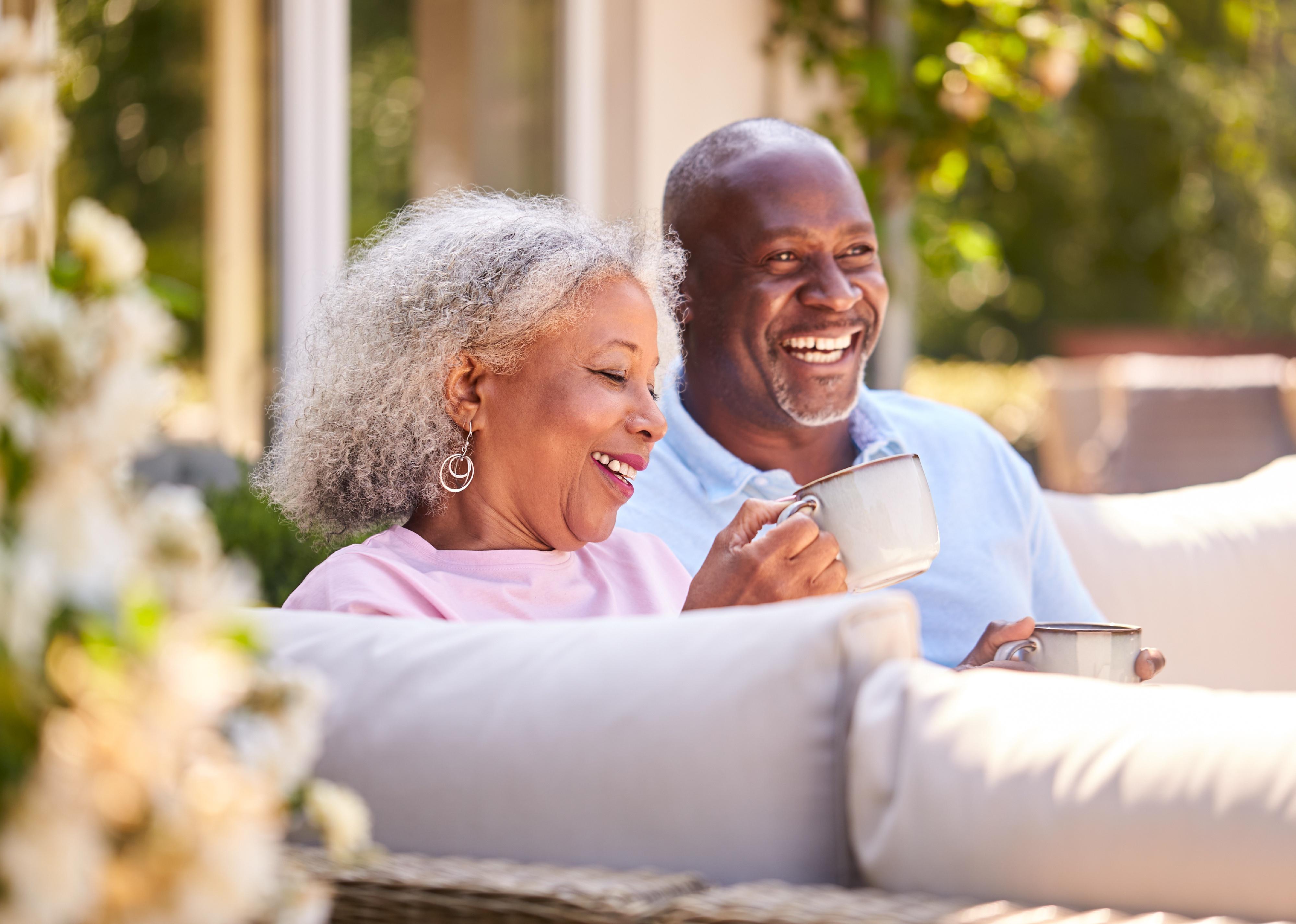 Retired couple sitting outdoors having coffee.