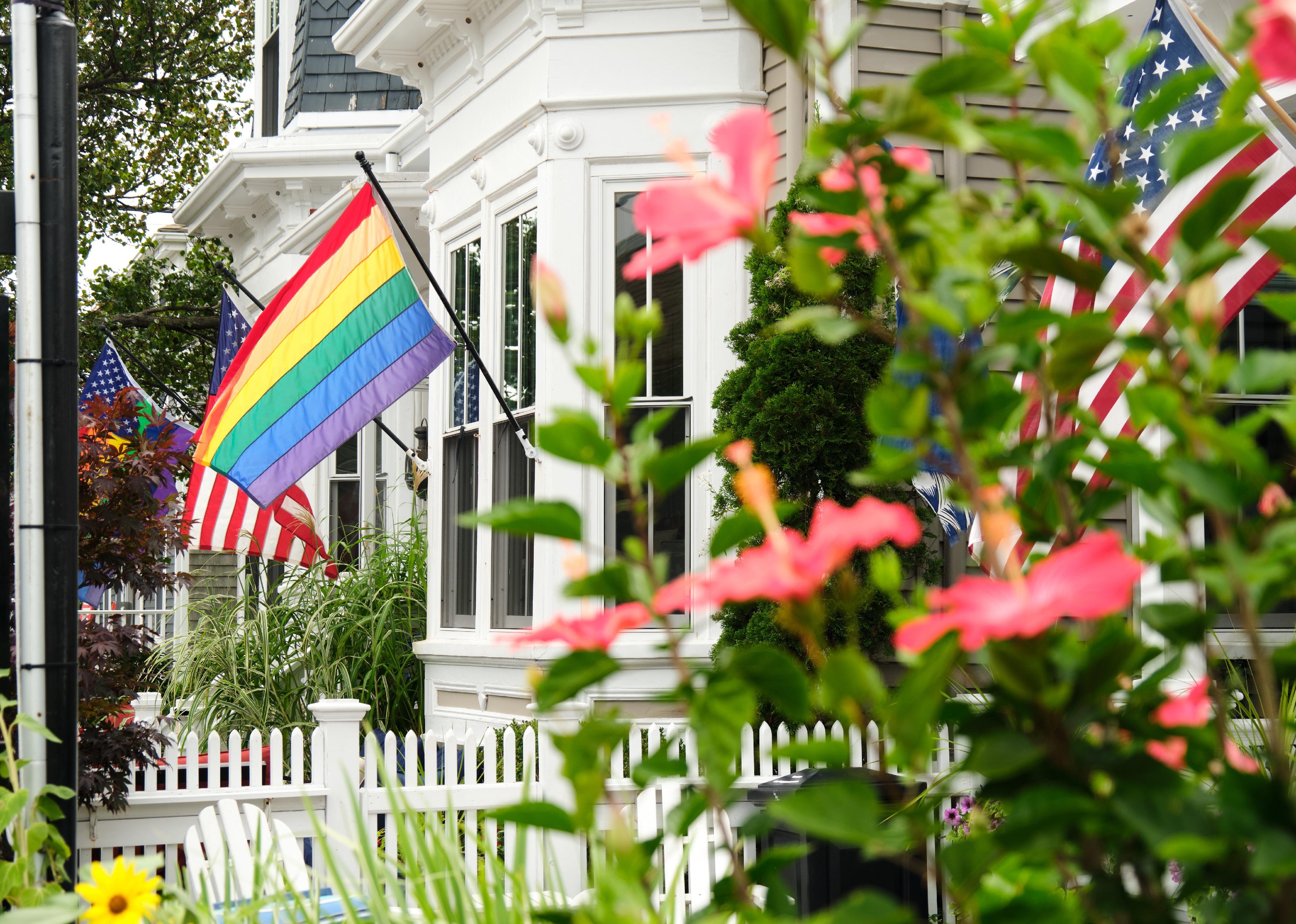 A rainbow pride flag is flanked by American flags on a house