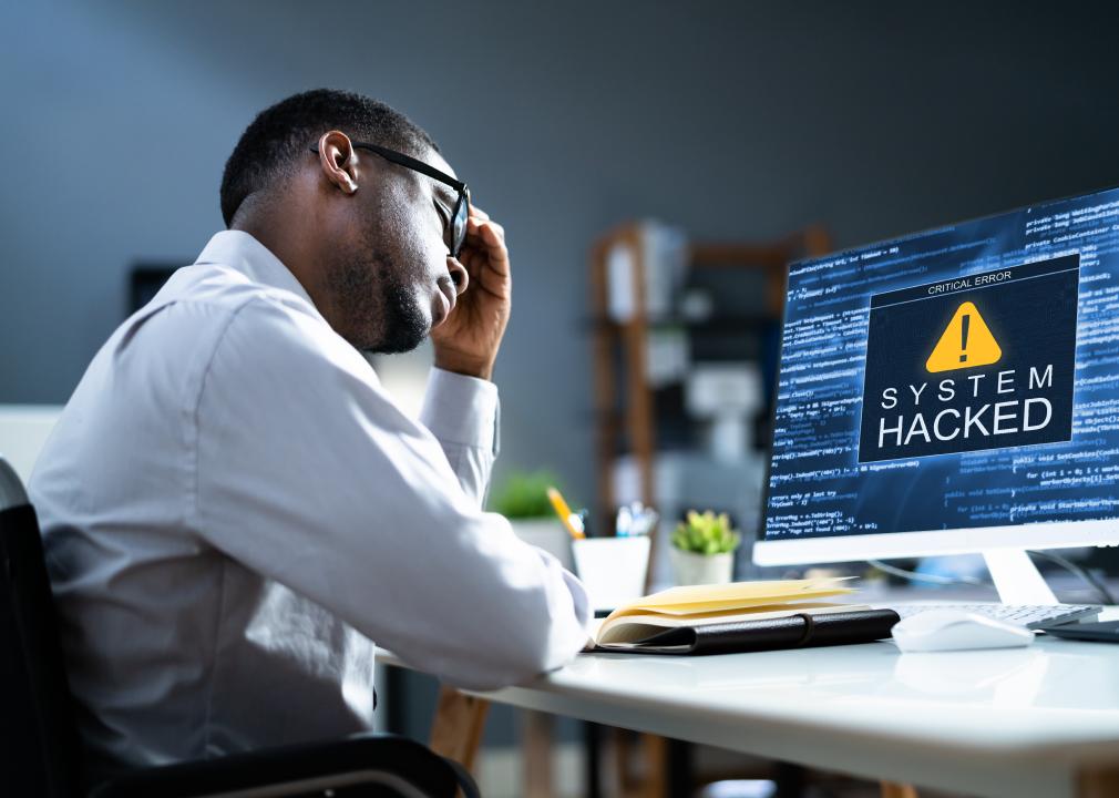 Person looking distraught at system-hacked notification on a computer.