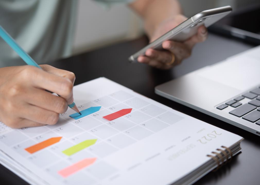 Woman taking notes on calendar desk on table. 