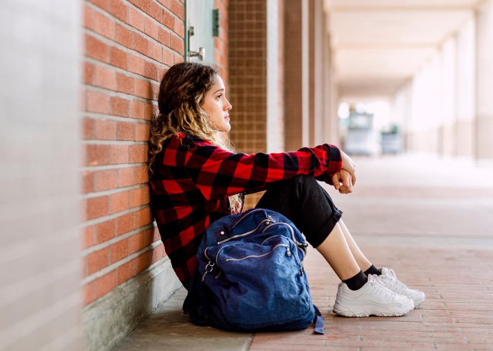 Girl sitting alone on ground at school.