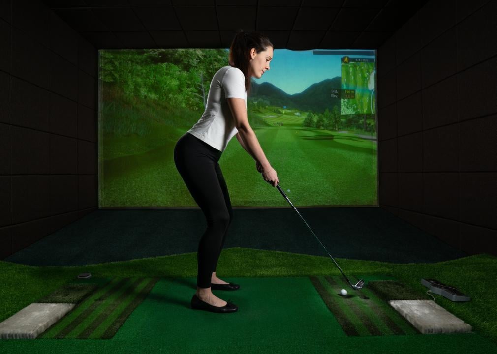 A girl playing on a golf simulator.