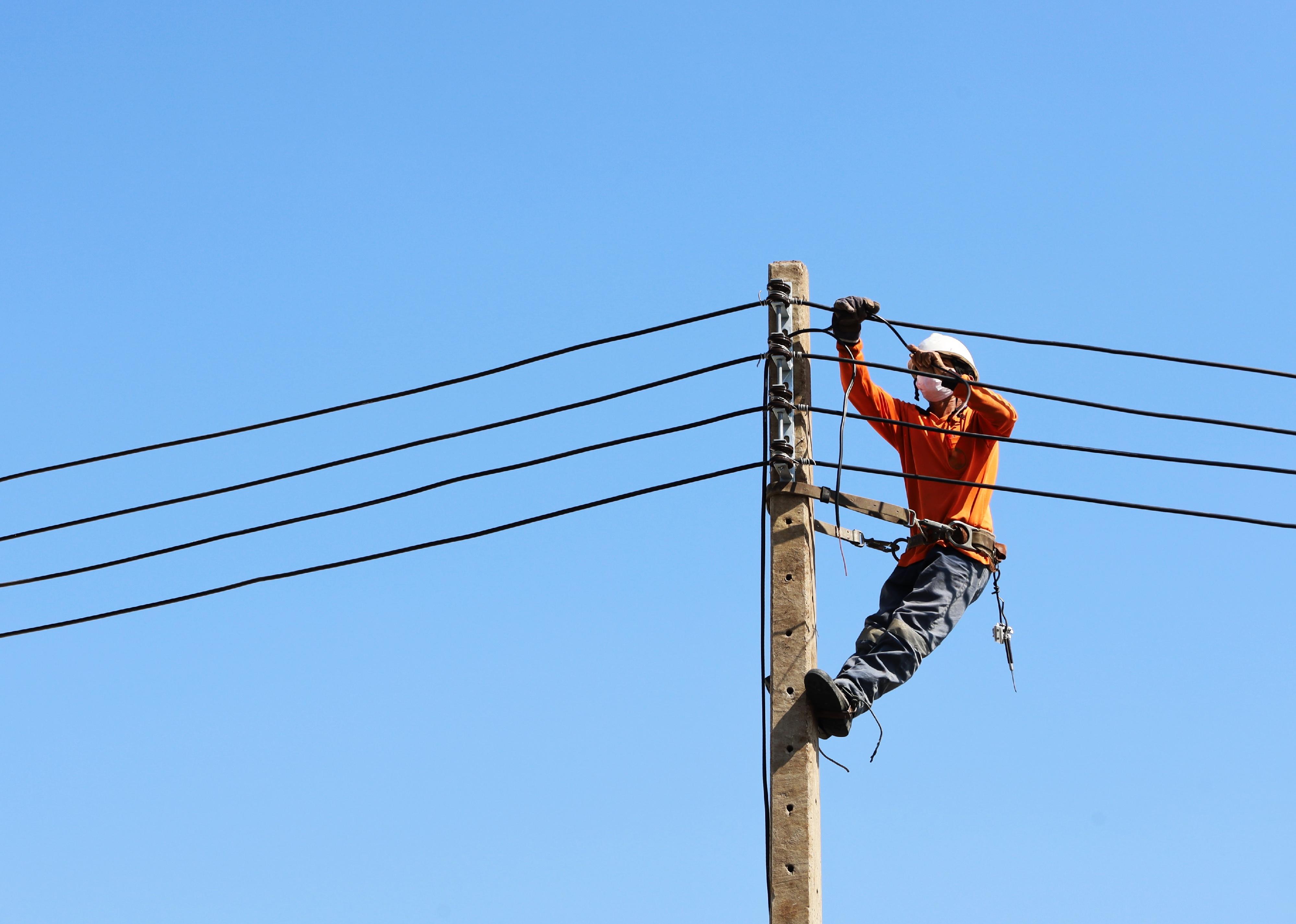 Technician connecting wires on electric poles.
