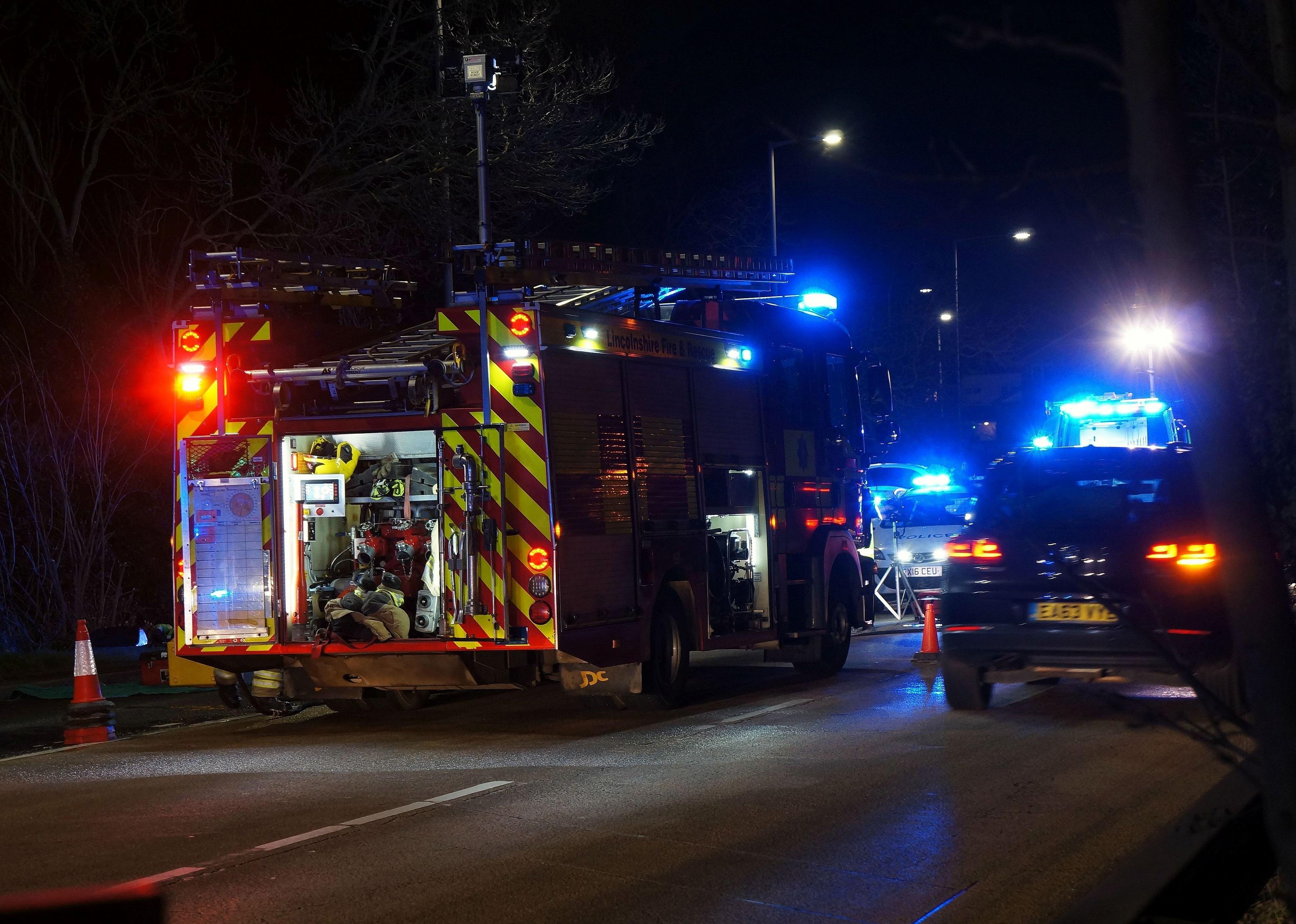 Scene of an accident at night with flashing lights from emergency vehicles.