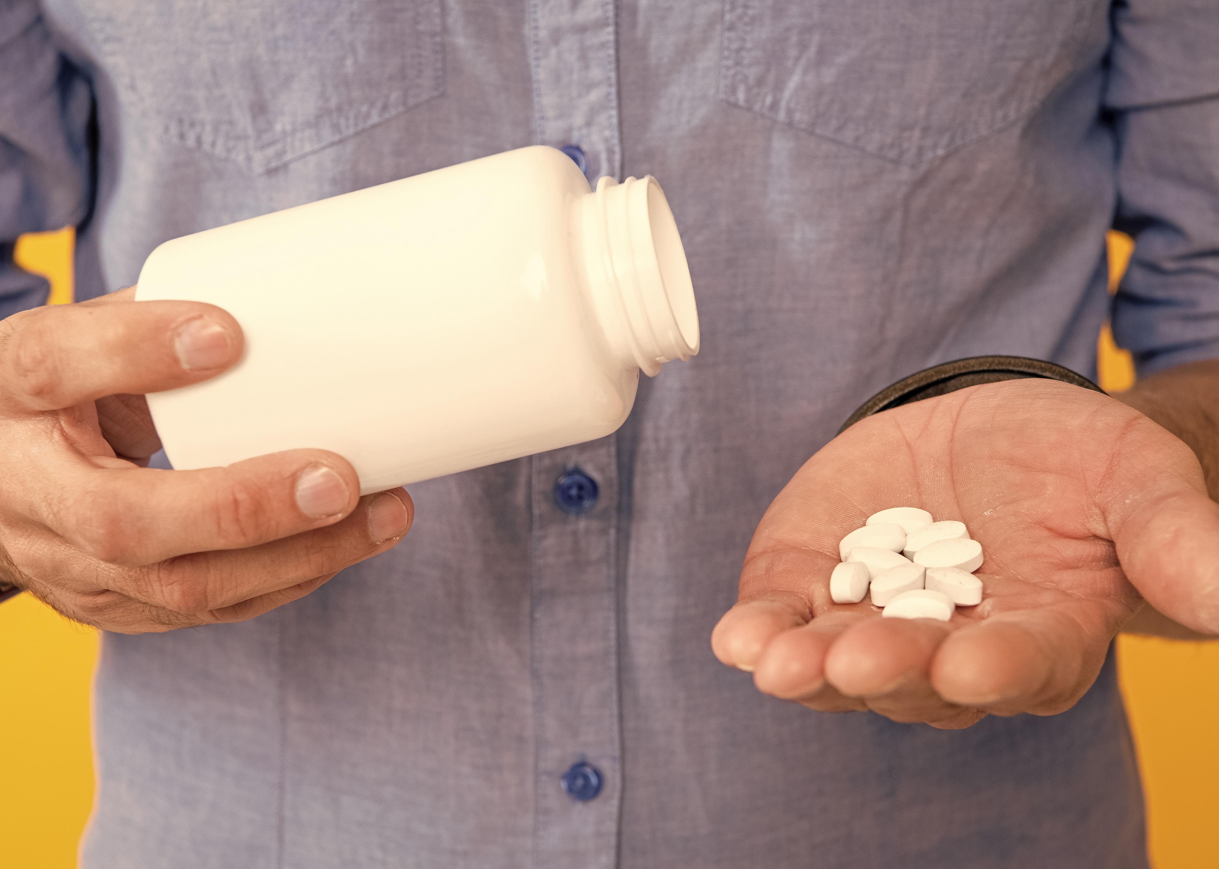 Cropped image of person holding pill jar. 