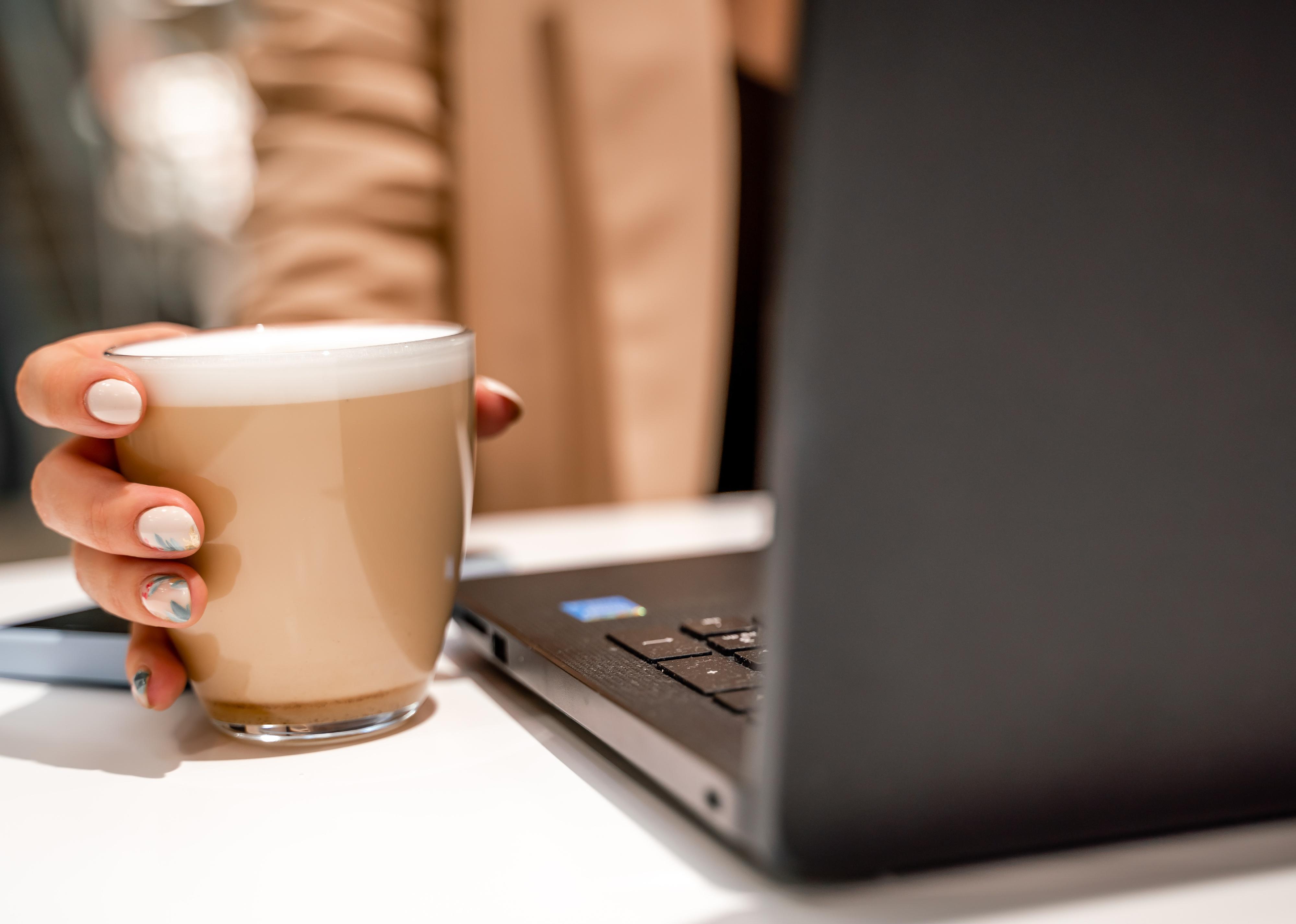 Close-up of female hands holding a large white cup of cappuccino..