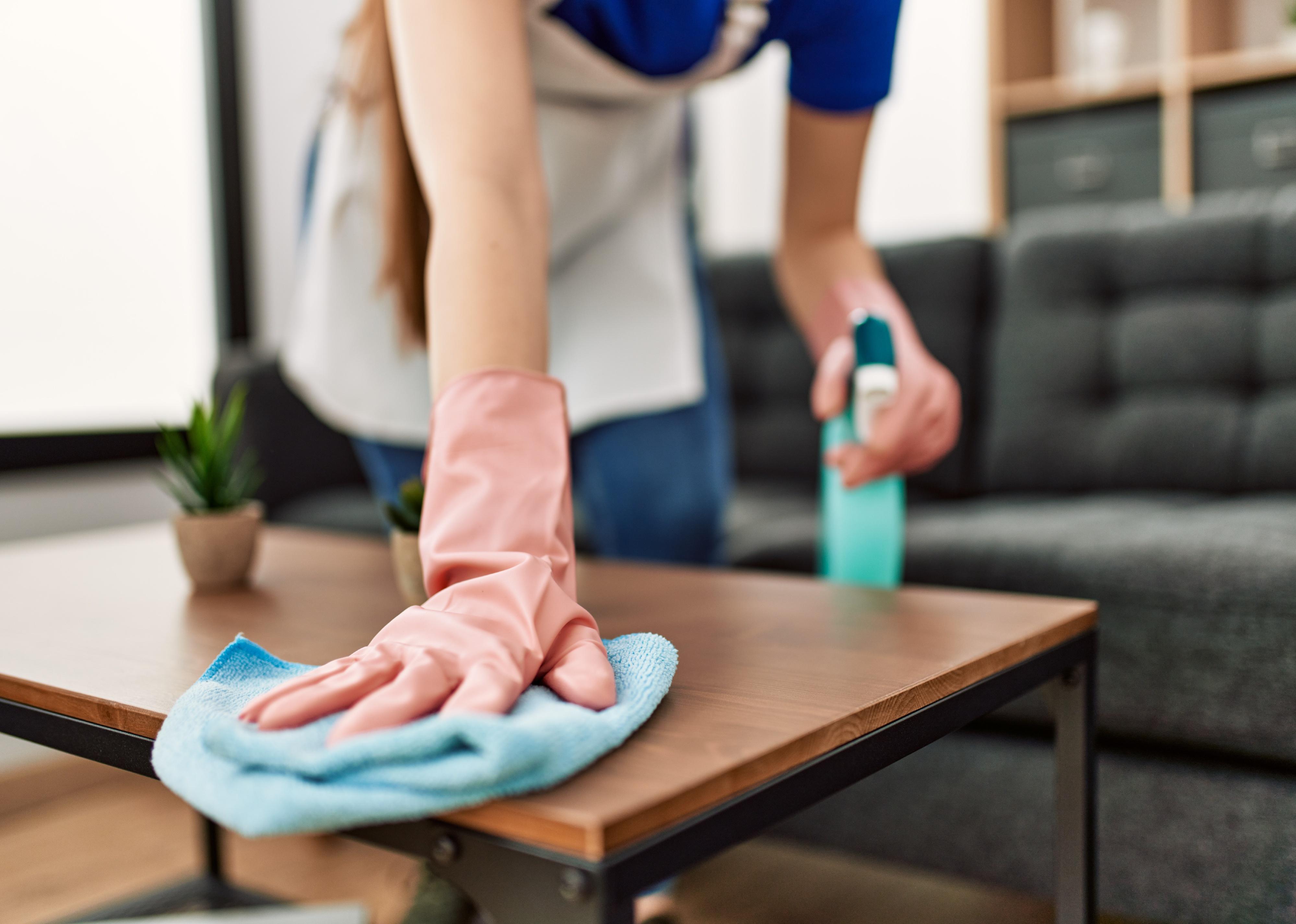 Woman cleaning table using rag and diffuser at home.