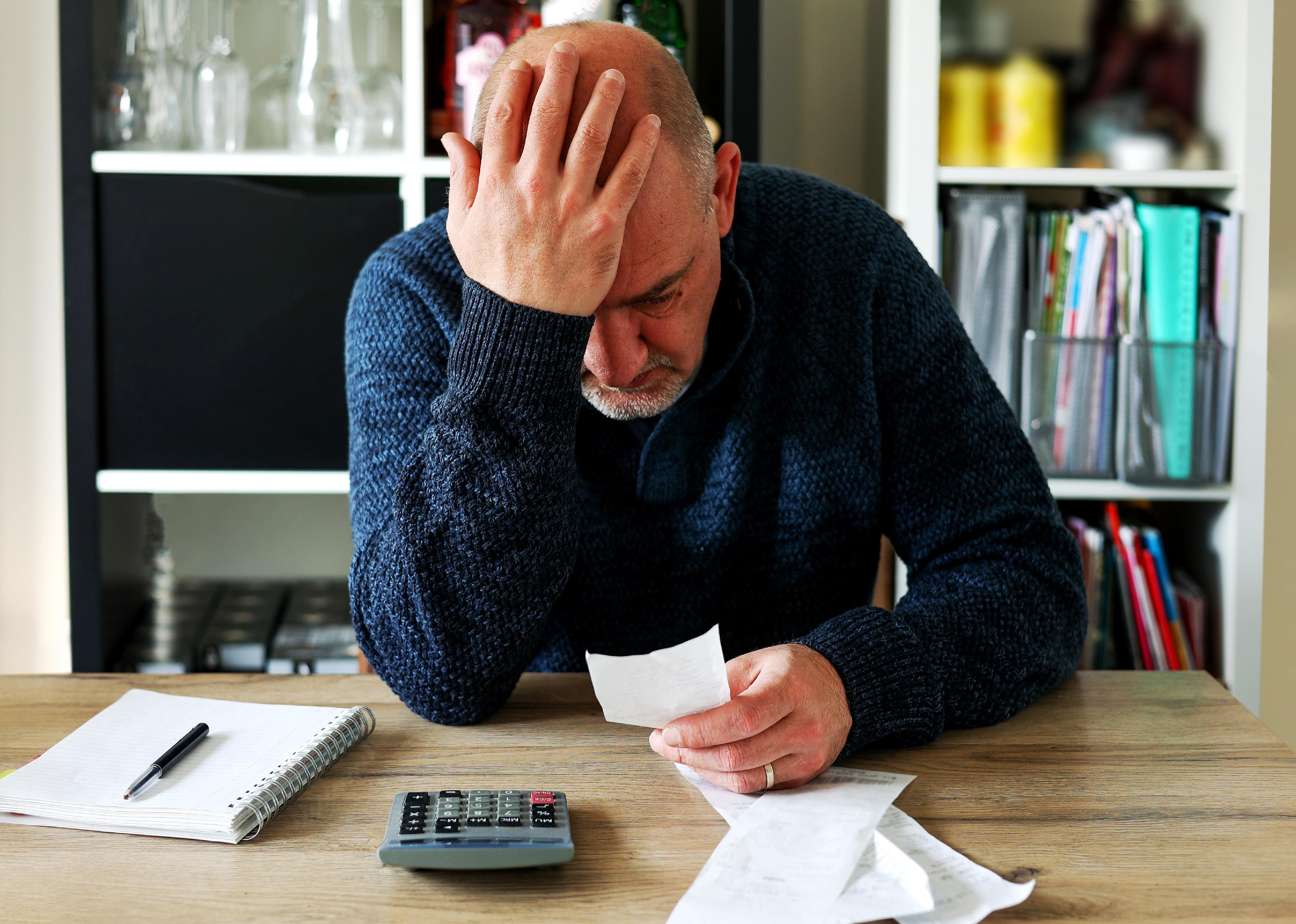 Man holding receipts from supermarket with calculator