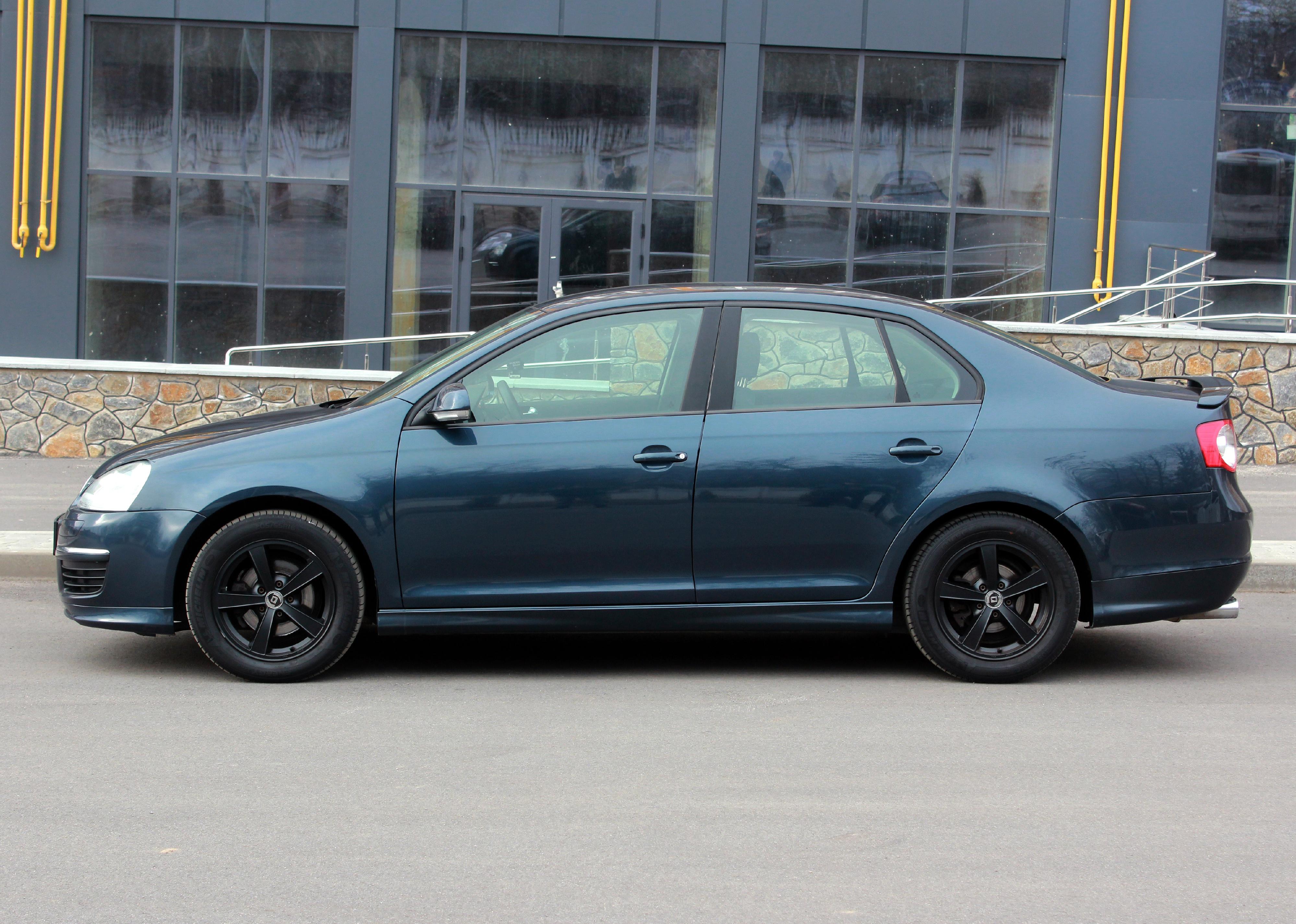 Gray-green Volkswagen Jetta on a city street. 