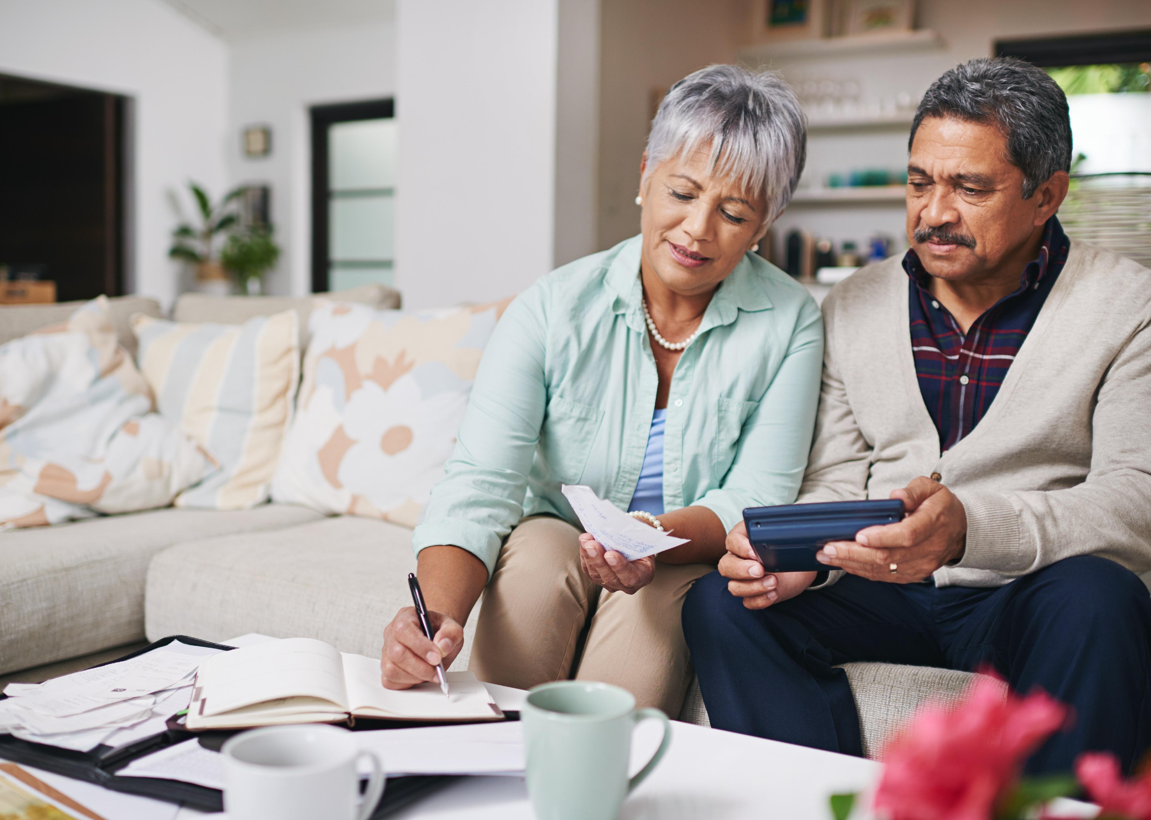 Elderly couple working on a budget on couch.