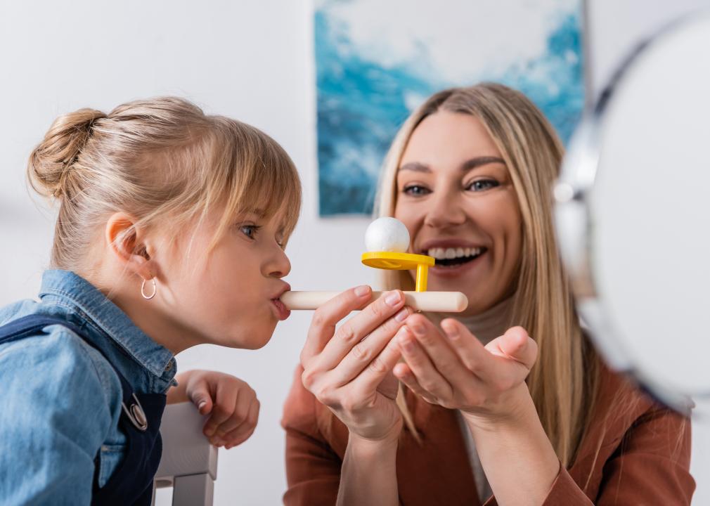 A therapist working with a child using a respiratory muscle trainer.