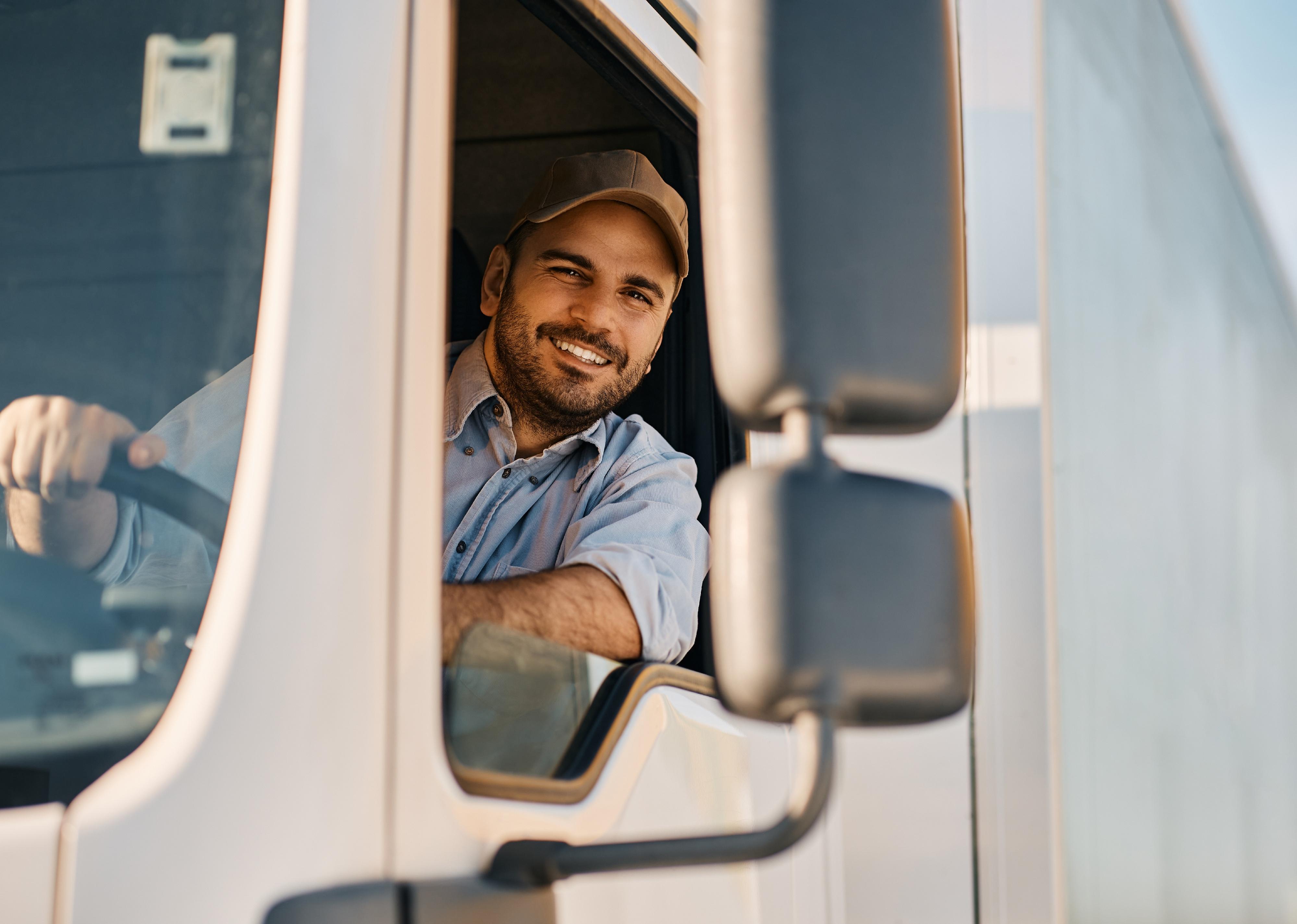 Happy truck driver driving his truck and looking at camera