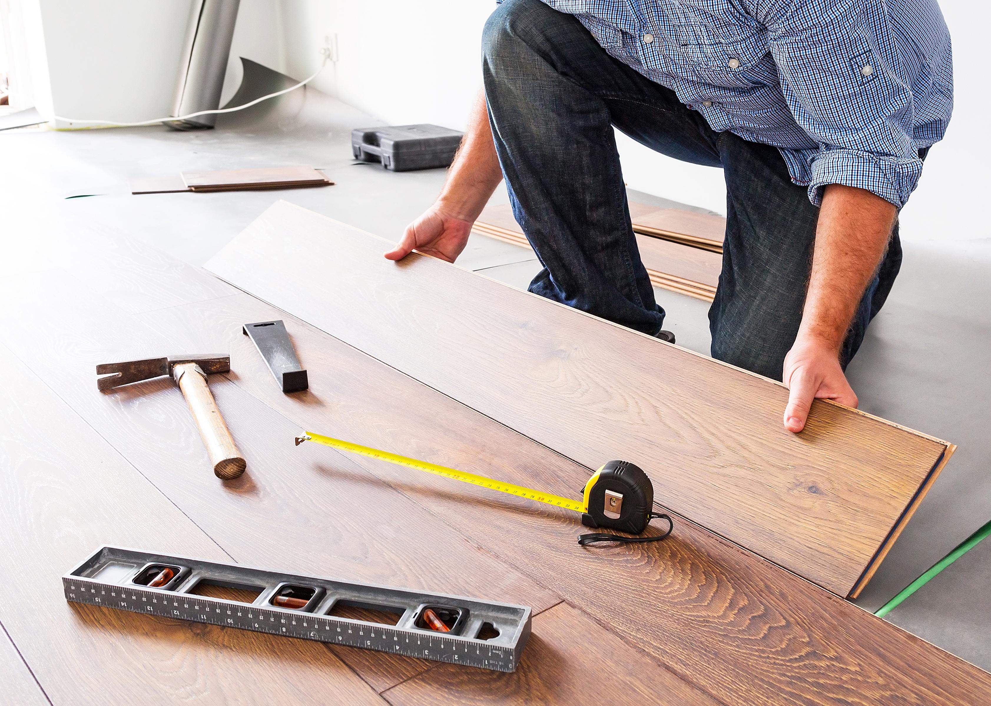 Person installing new laminated wooden floor.