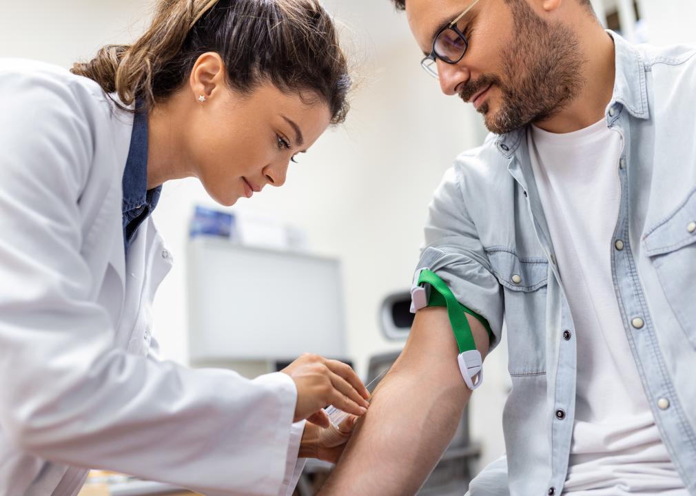 A phlebotomist collecting a blood sample from a patient in lab.